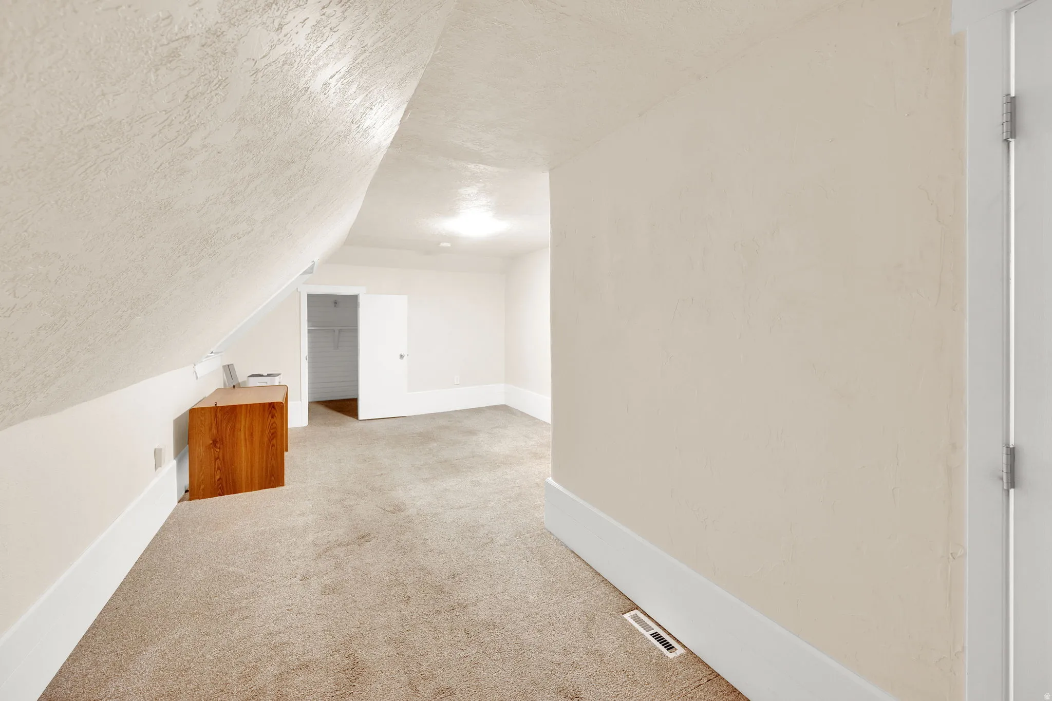 Carpeted room with sloped ceilings, recessed lighting, and a neutral color palette