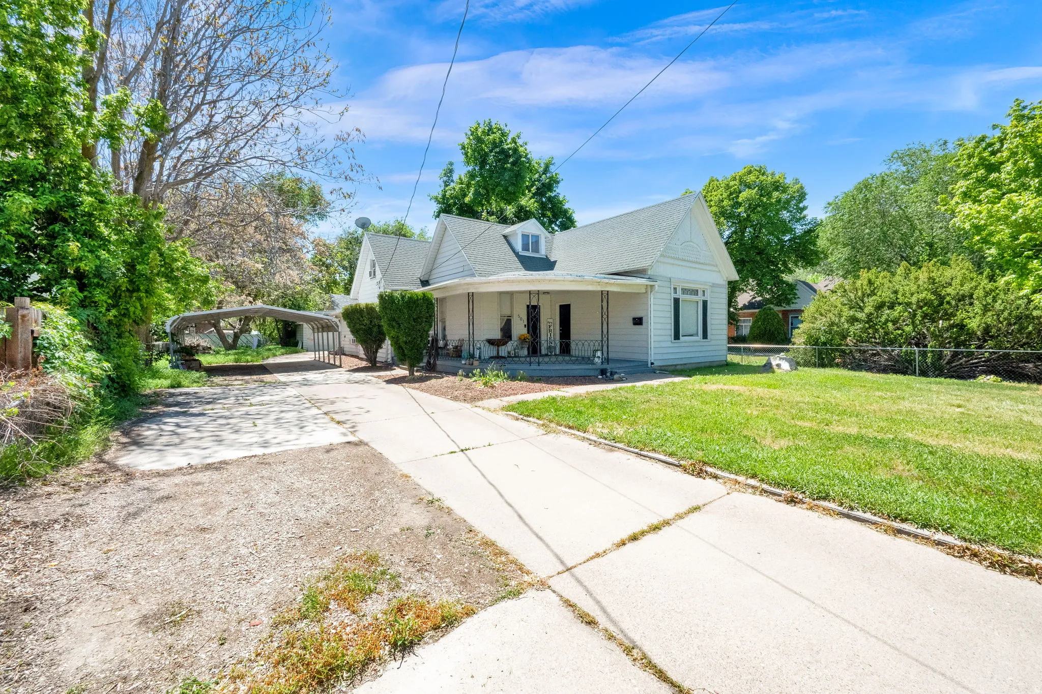 Traditional-style residence with white siding, a covered front porch, and a dormer window