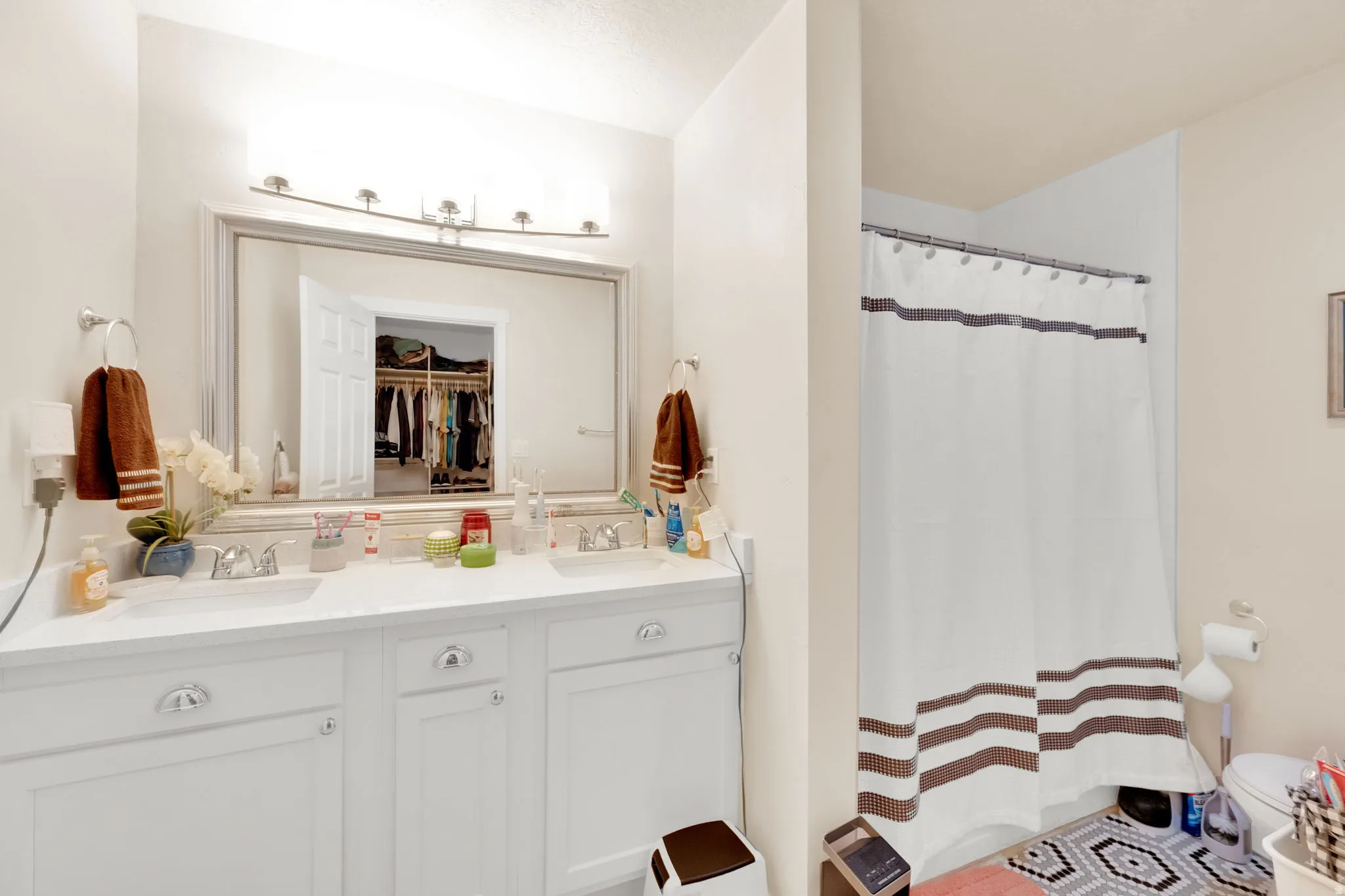 Dual vanity with chrome fixtures and ample counter space, complemented by a large framed mirror with overhead lighting