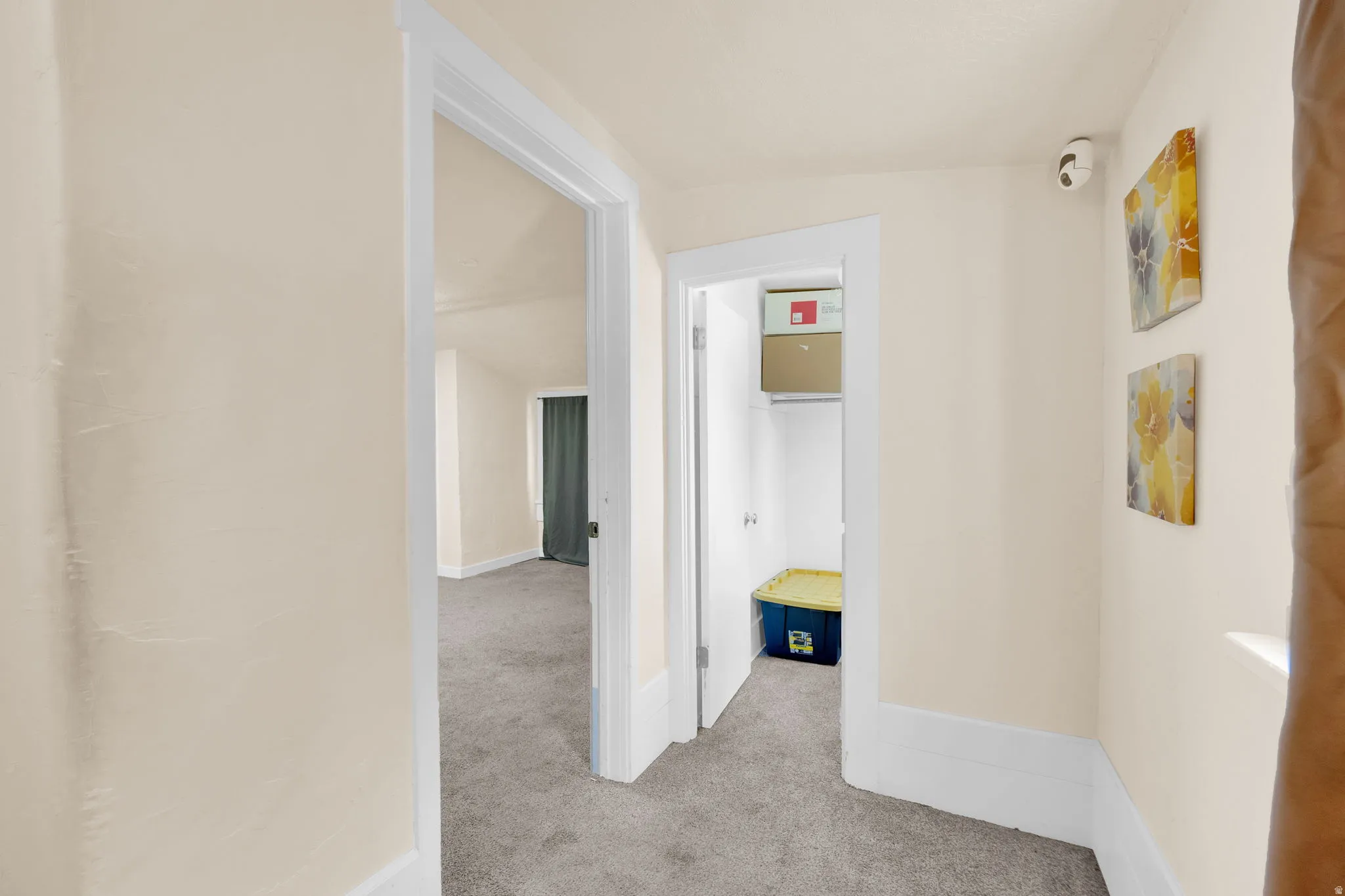 Hallway with neutral wall tones, white trim, and gray carpeted flooring