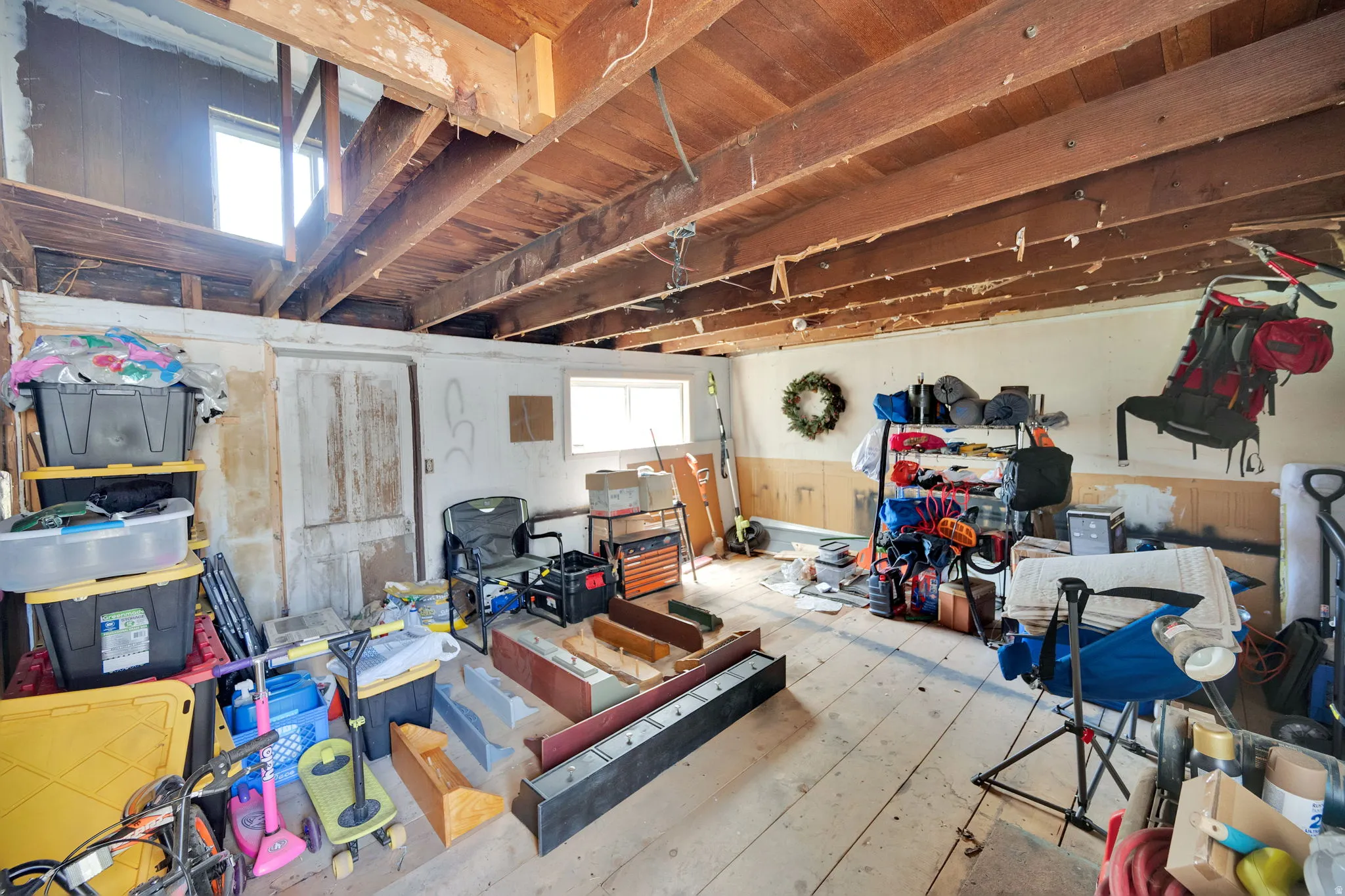 Exposed wooden ceiling beams spanning across the space, with natural light entering through two windows
