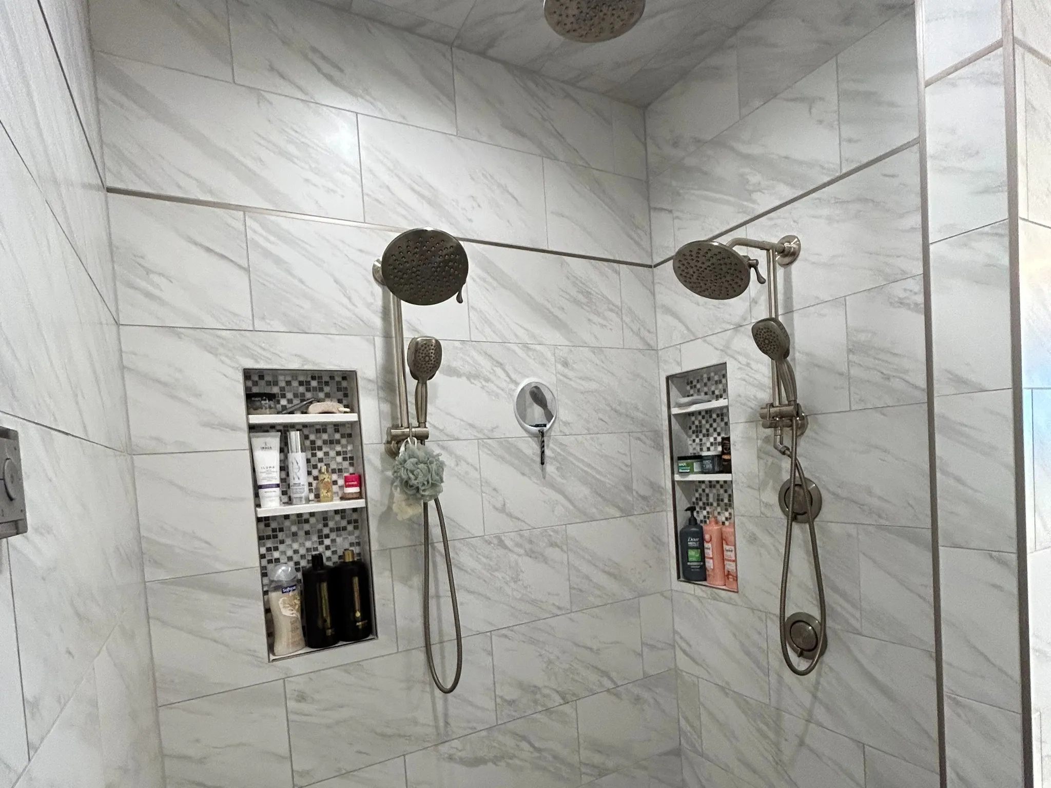 Expansive walk-in shower featuring white marble-look wall tiling and a gray tiled floor