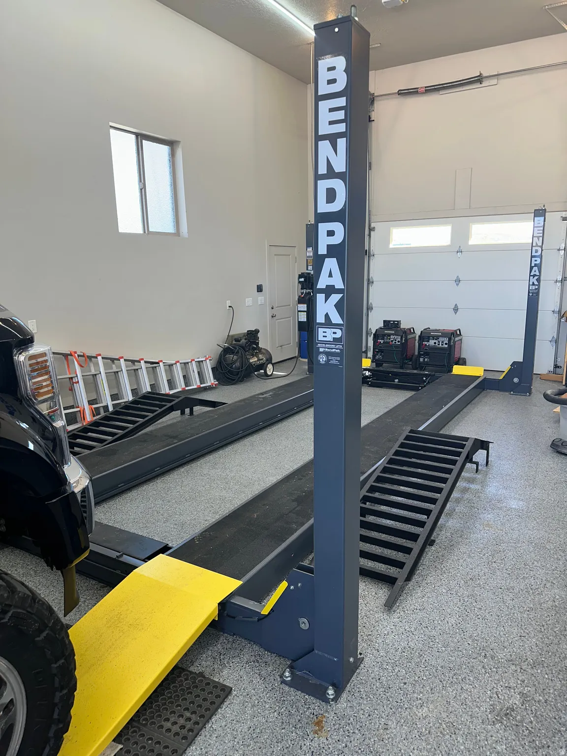 Spacious garage featuring a professional-grade vehicle lift, durable epoxy flooring, and two overhead garage doors
