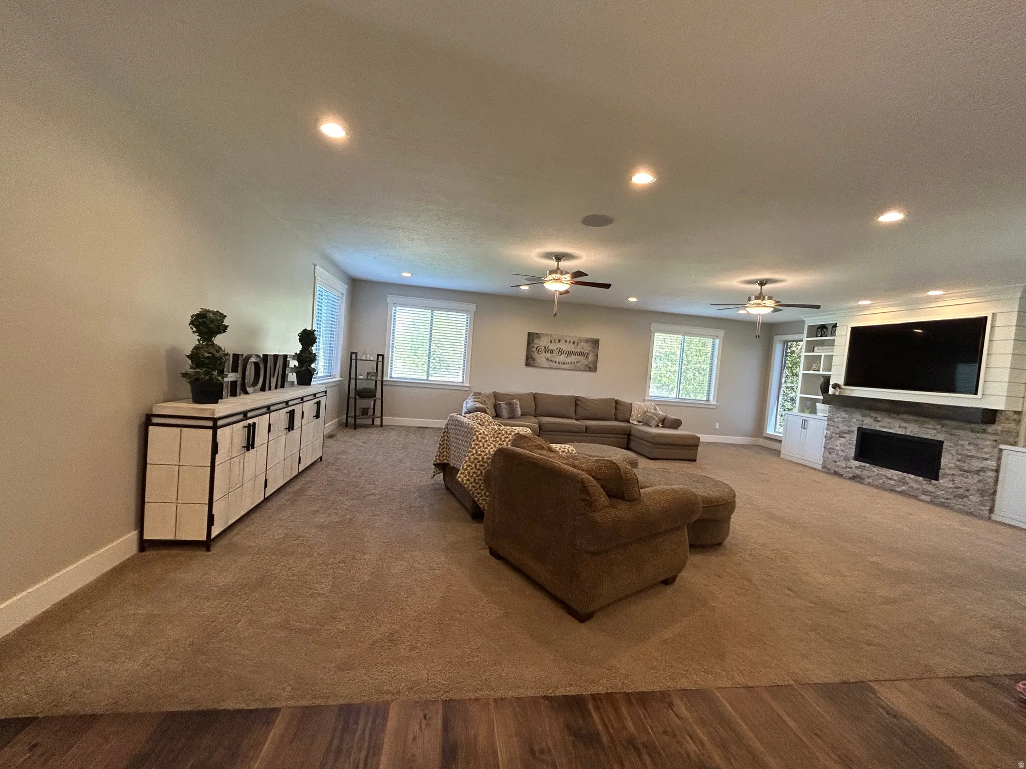 Spacious living area featuring neutral carpet and wood-finish flooring, recessed lighting, and ceiling fans