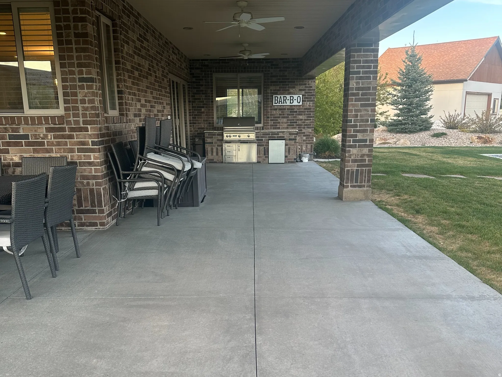 Covered patio featuring an outdoor kitchen with built-in grill, brick facade, recessed lighting, and ceiling fans