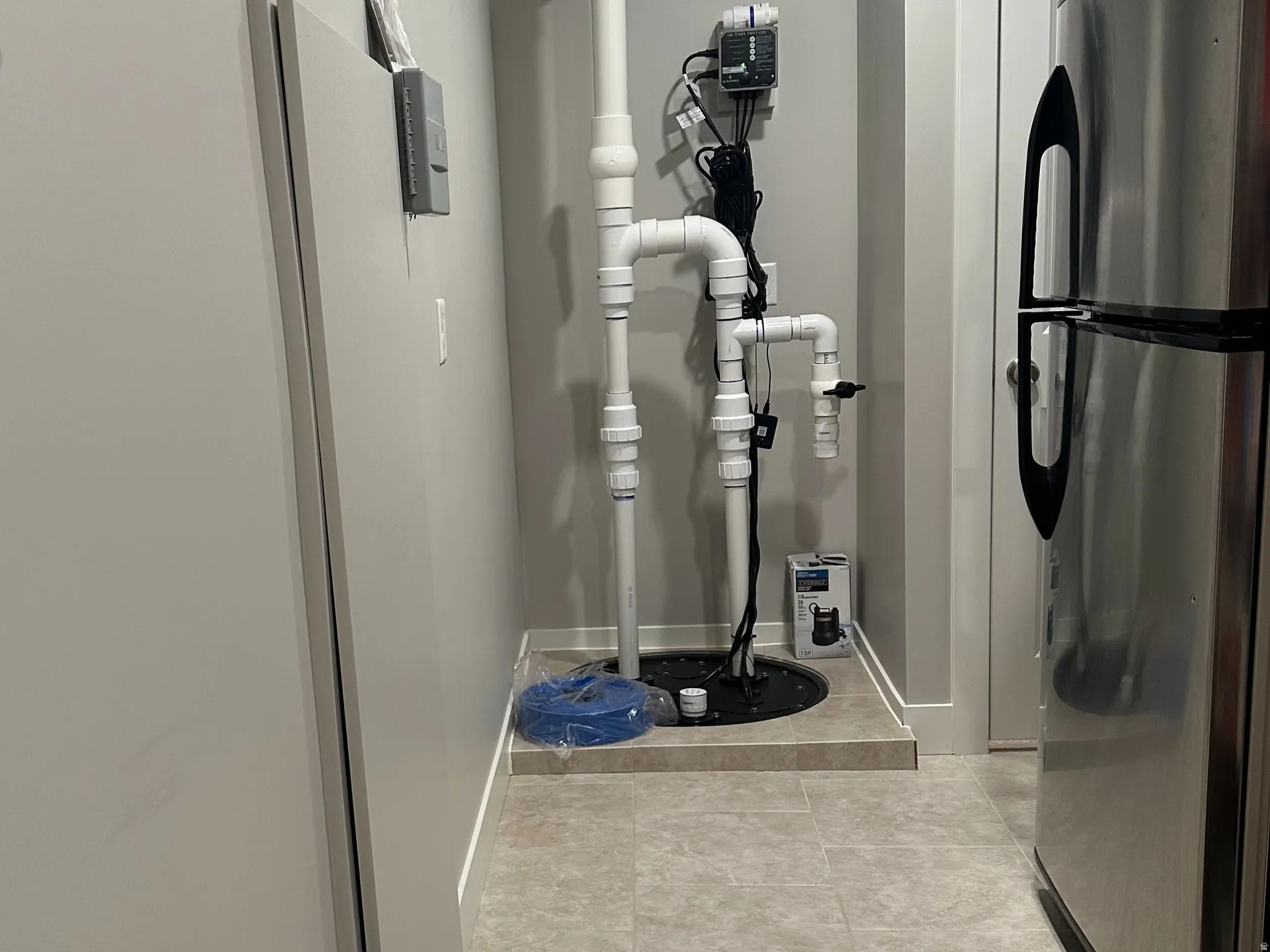 Utility area featuring a sump pump system with PVC piping, recessed lighting, and durable tile flooring