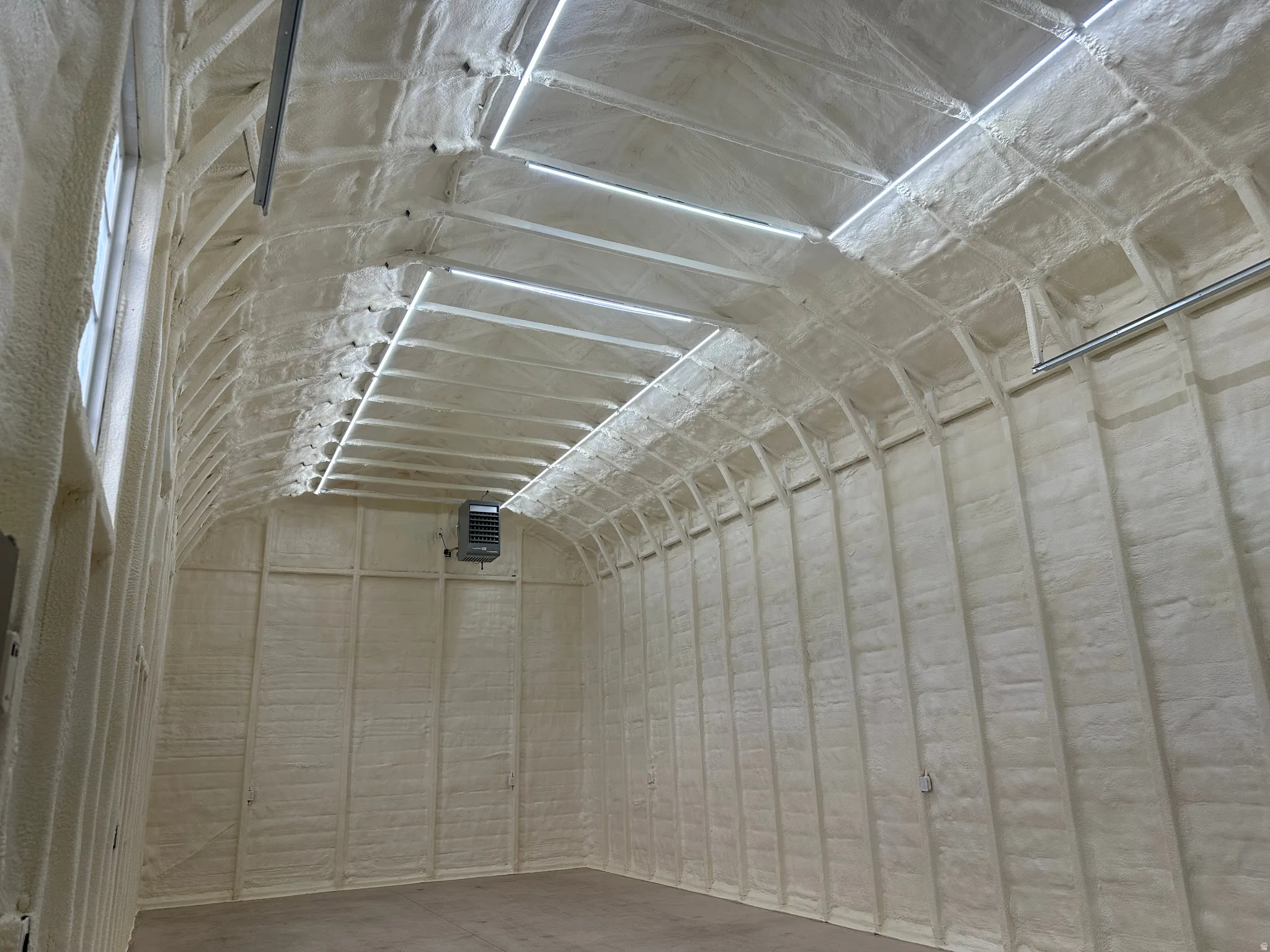 Interior space featuring extensive spray foam insulation on walls and a high arched ceiling