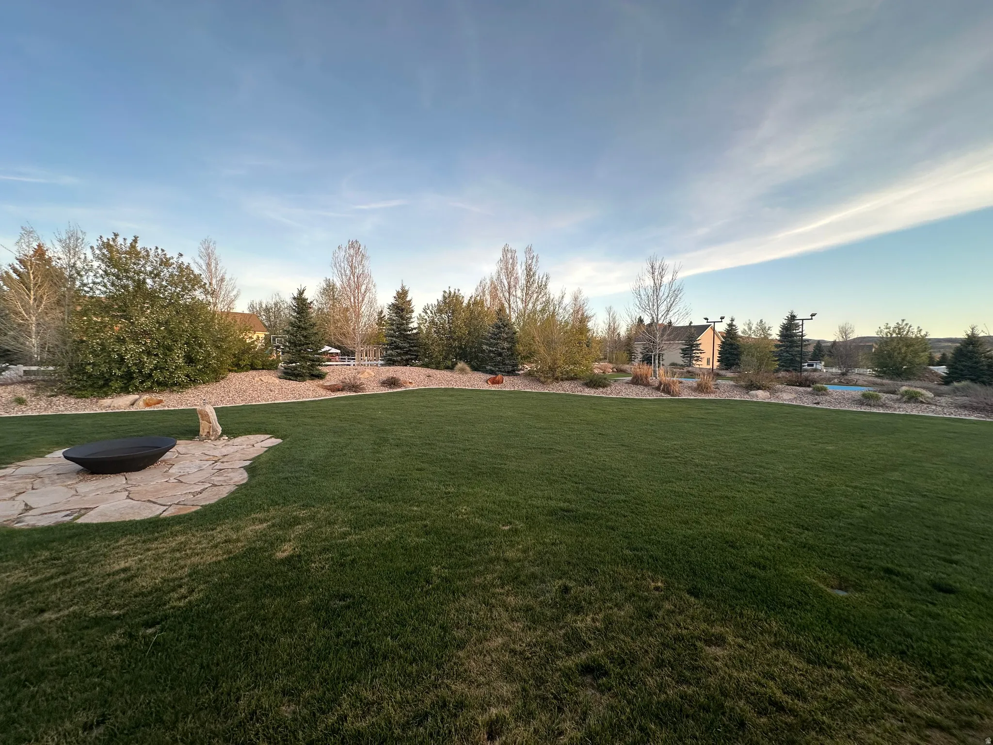 Expansive lawn with a flagstone patio featuring a built-in fire pit