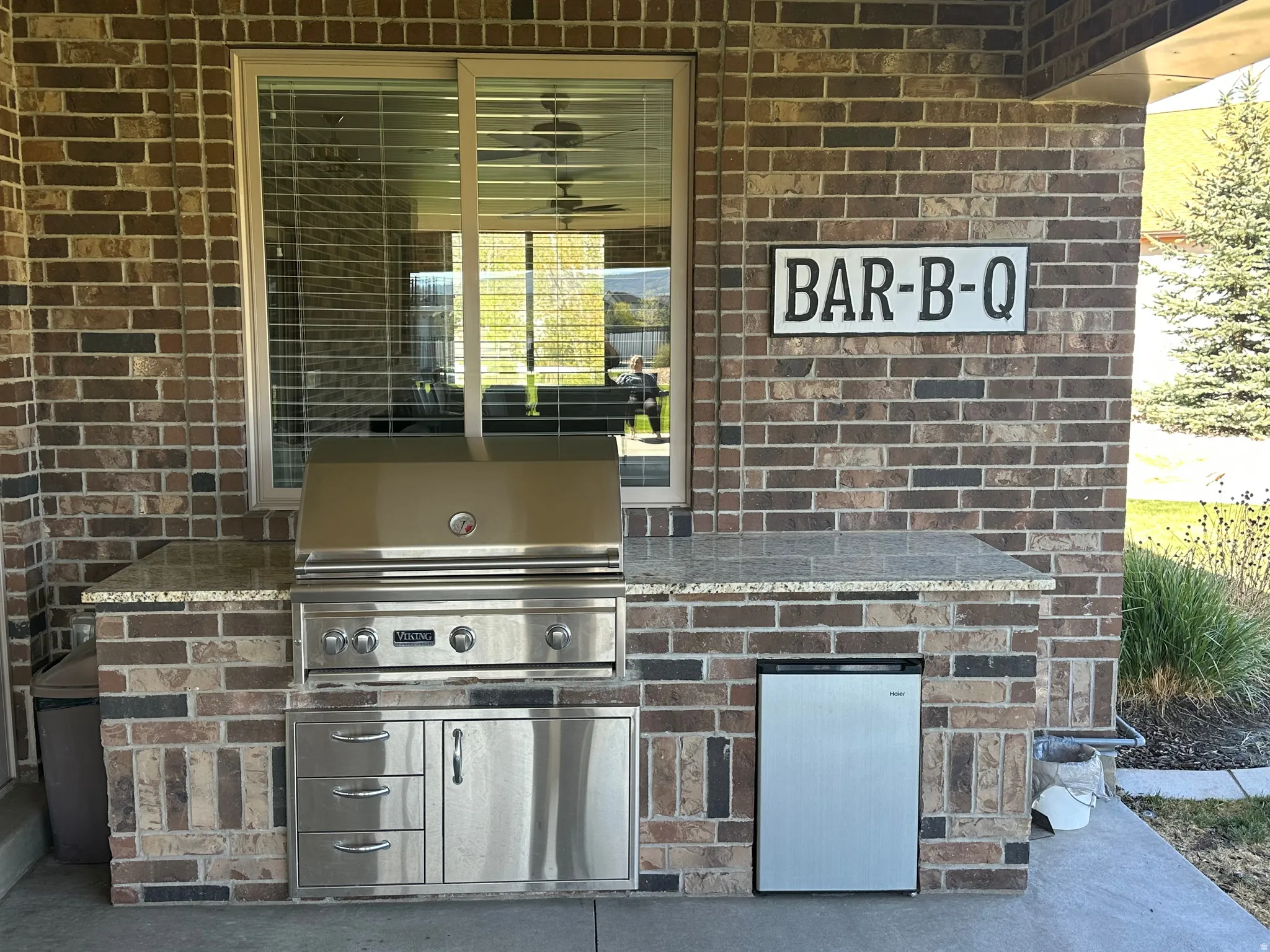 Outdoor kitchen featuring a built-in stainless steel grill, integrated storage drawers, and a compact refrigerator