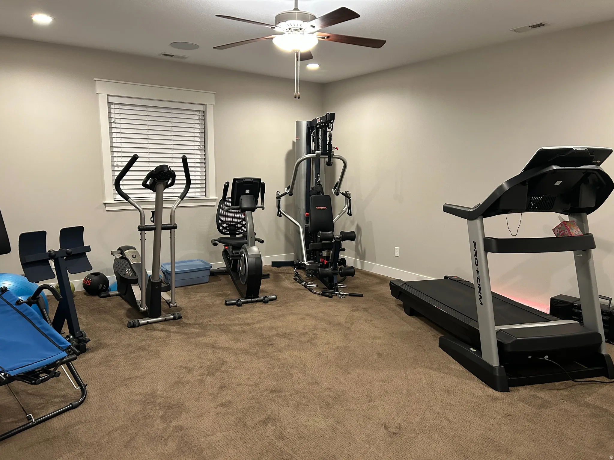 Carpeted room with a window featuring blinds, recessed lighting, and a ceiling fan