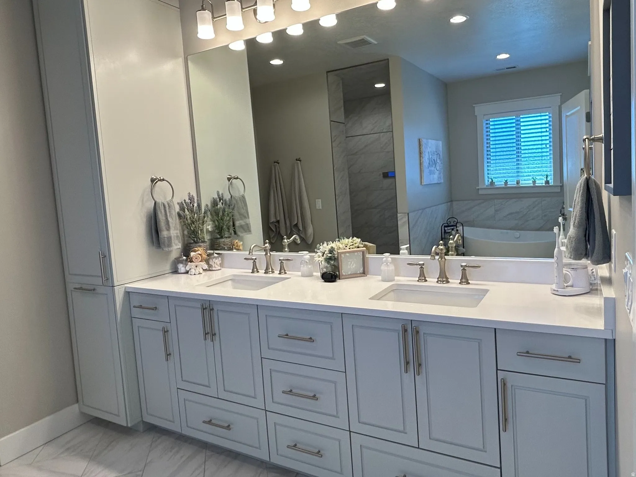 Dual vanity with light-toned cabinetry, integrated sinks, and polished hardware