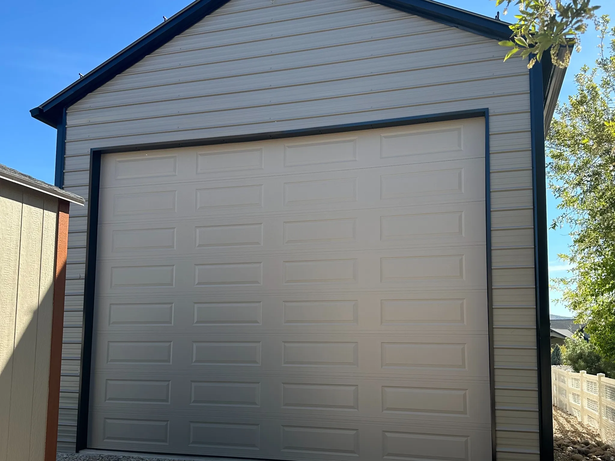 Detached structure featuring a paneled garage door, horizontal siding, and a dark trim roofline