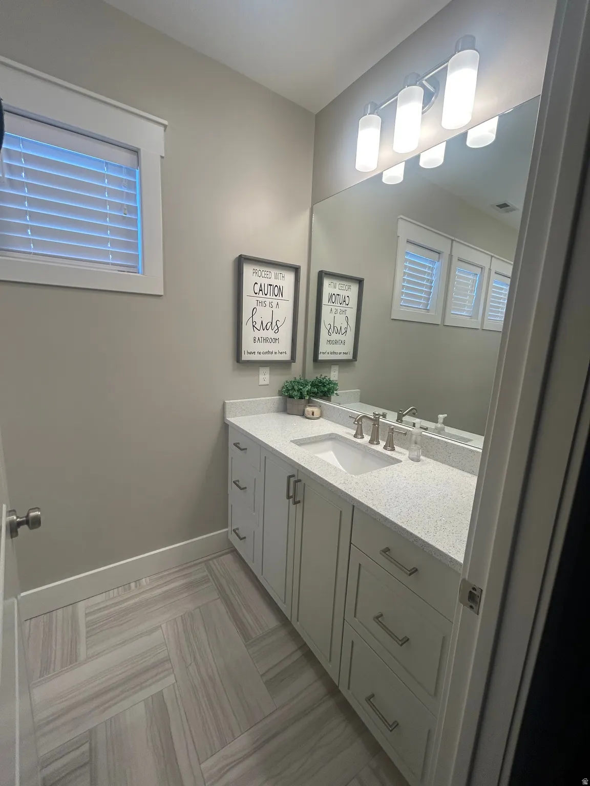 Spacious vanity featuring light gray cabinetry, a speckled countertop, and an undermount sink with brushed nickel fixtures