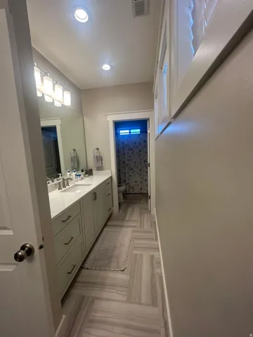 Bathroom featuring a spacious dual vanity with light-toned cabinetry and a light-colored countertop