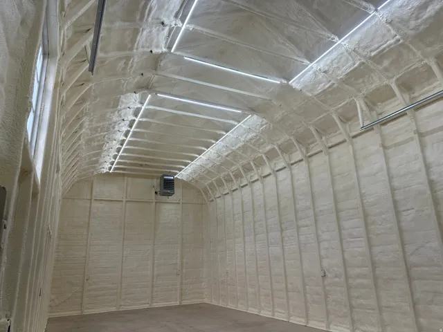 Interior space featuring extensive spray foam insulation on walls and a high arched ceiling