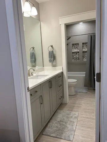 Contemporary bathroom featuring a light gray vanity with brushed nickel hardware, a white countertop, and an undermount sink