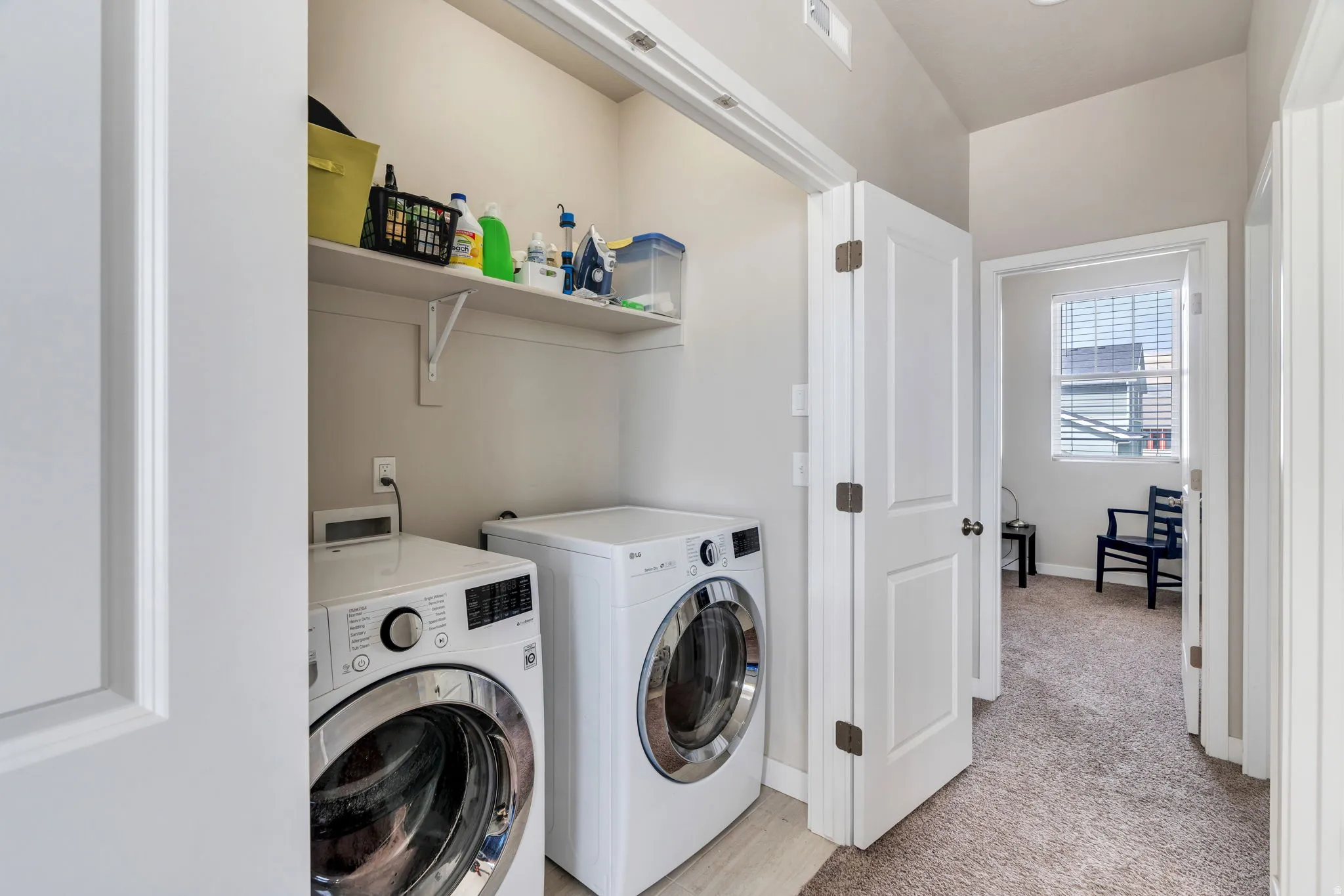 Convenient dedicated laundry area upstairs featuring a built-in shelf, light wood-finish flooring, and white walls