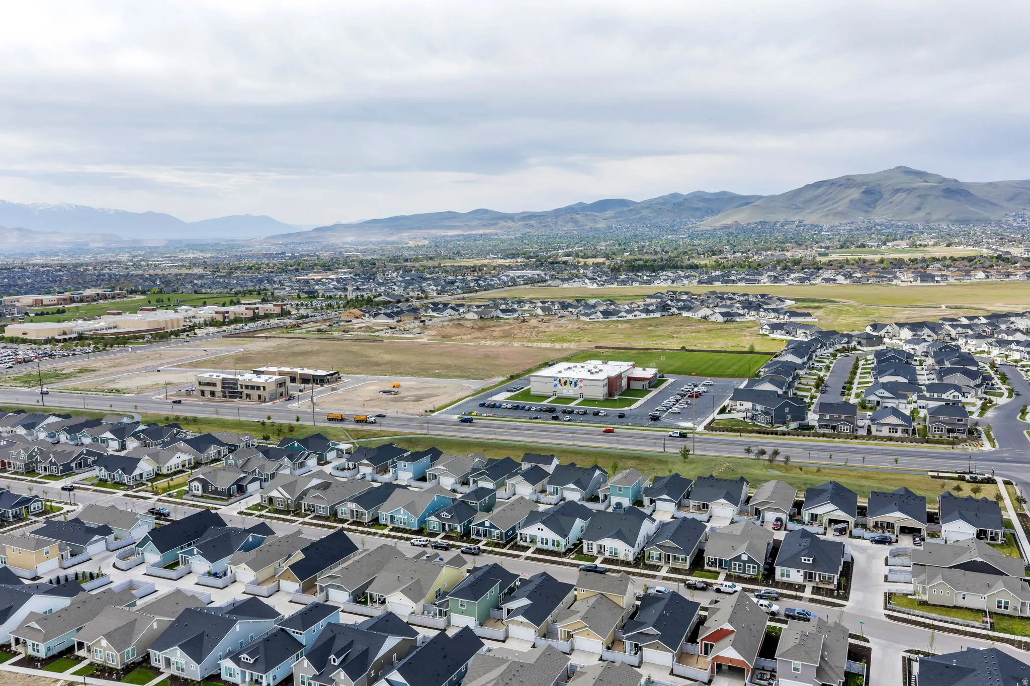 Expansive residential development featuring a structured neighborhood layout, mountain backdrop, paved roads, and varied home exteriors