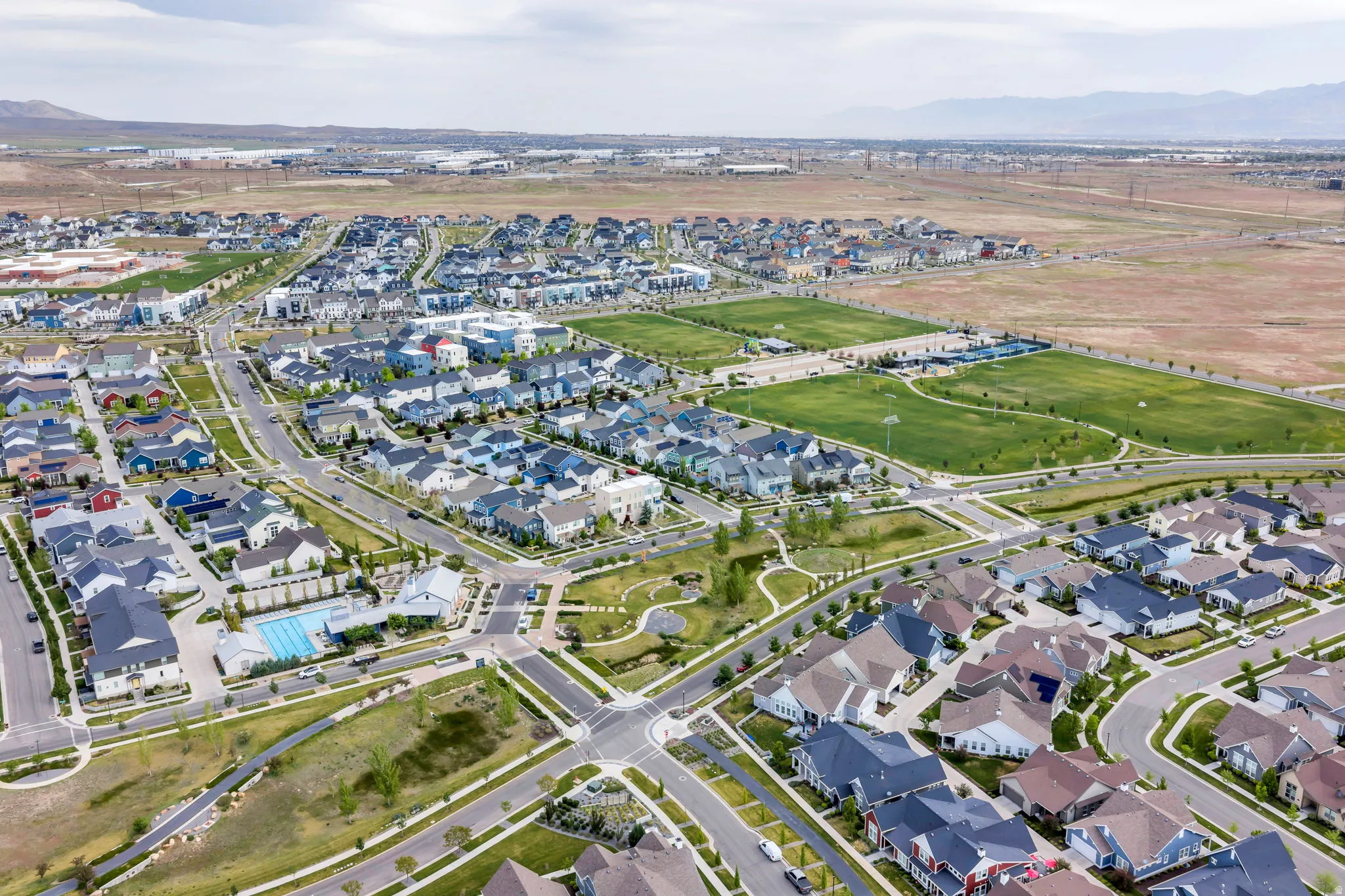 Residential development featuring extensive green spaces, a community pool, and varied architectural styles