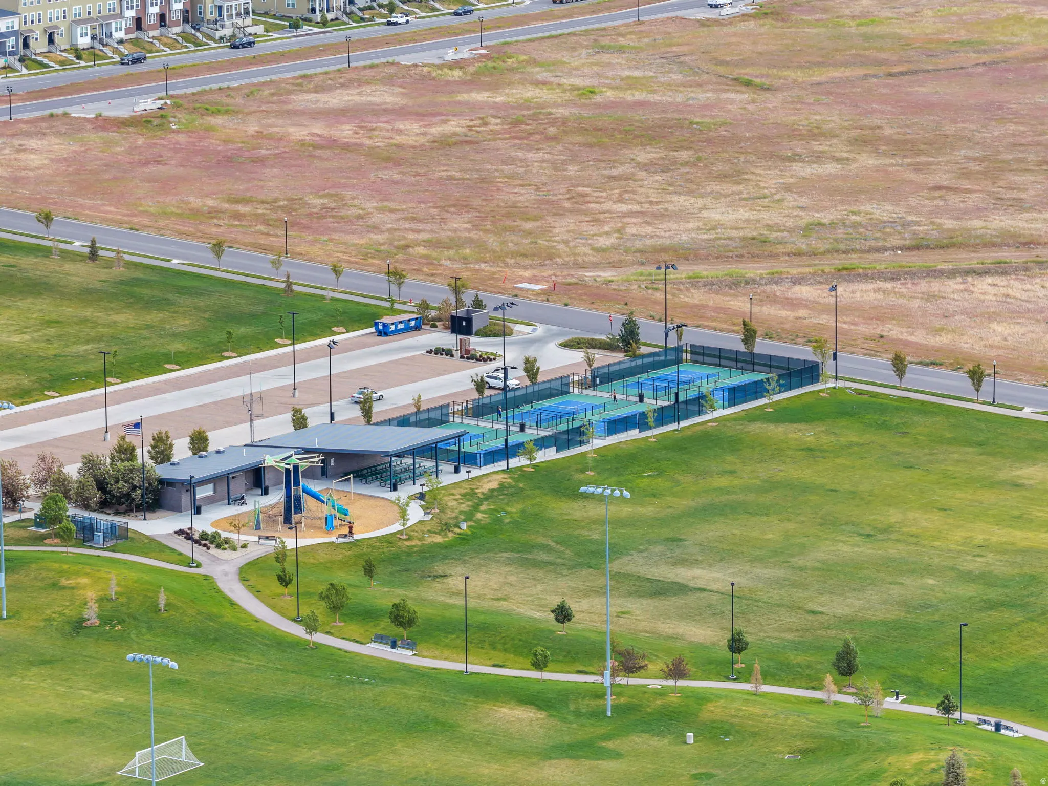Community recreation area nearby featuring multiple pickleball courts, a covered pavilion, and a playground structure