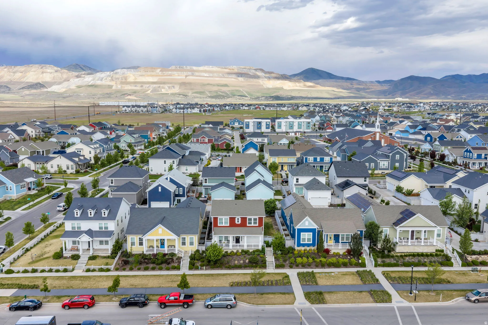 Aerial perspective showcasing a residential community with diverse single-family homes, manicured streetscapes, and mountainous terrain in the background