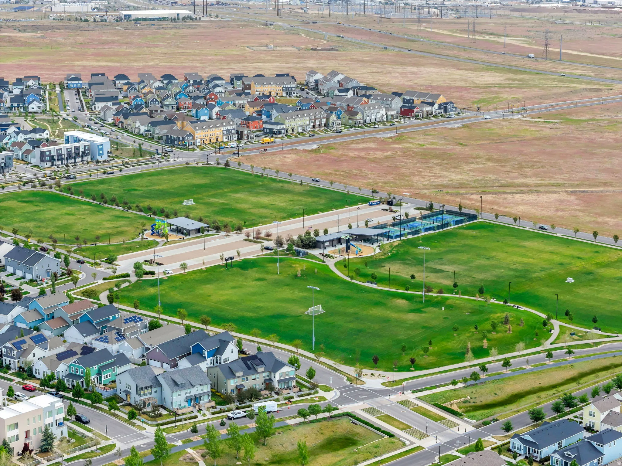 Expansive green spaces featuring multiple sports fields, paved pathways, and tennis courts