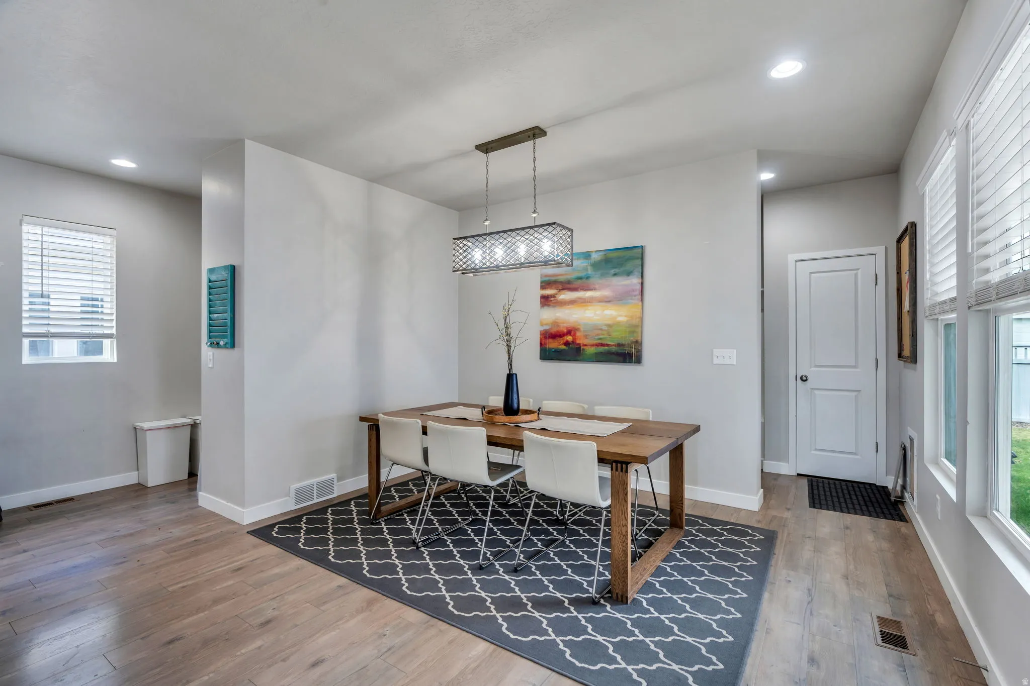 Dining area featuring wood-finish flooring, recessed lighting, and a linear pendant fixture