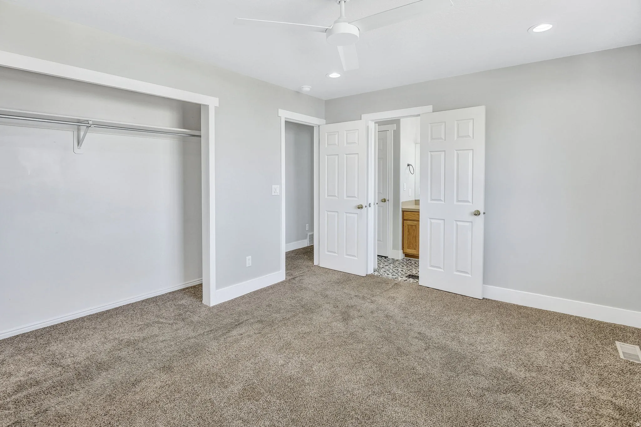 Spacious room featuring neutral carpeting, light gray wall paint, and white trim