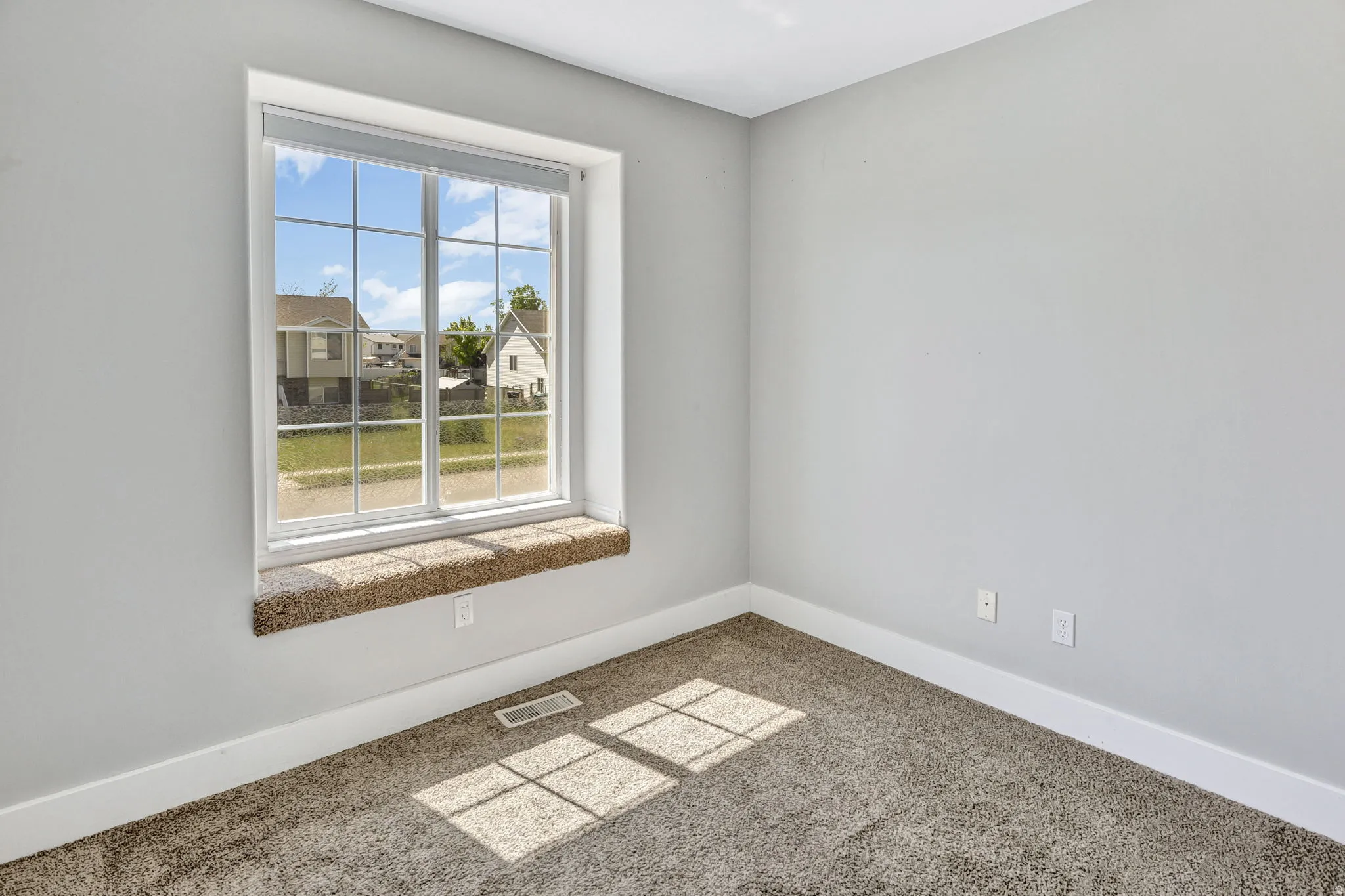 Windowed room featuring light gray walls, white trim, and a carpeted floor