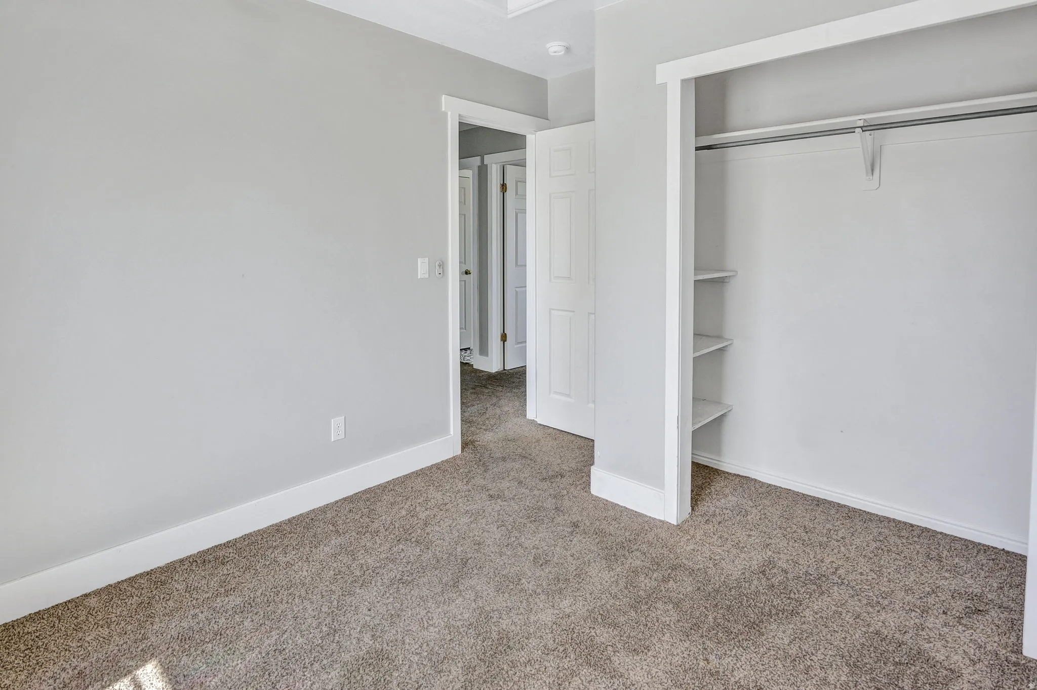 Carpeted room featuring light gray walls and white baseboards