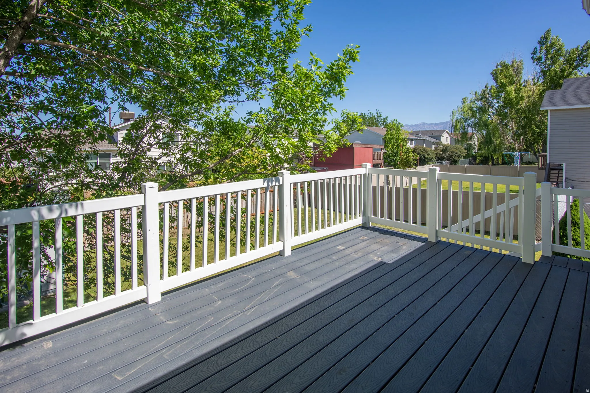 Spacious outdoor deck featuring dark-toned composite decking, white railing, and a gate