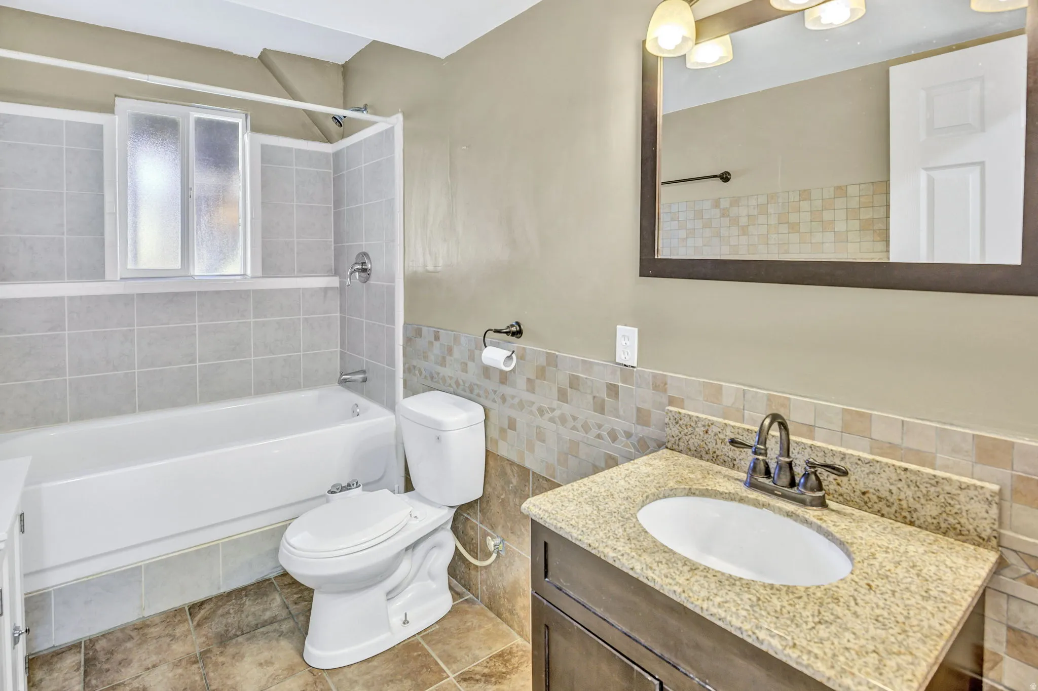 Bathroom featuring a single vanity with a light-toned granite countertop, undermount sink, and a dark-framed mirror