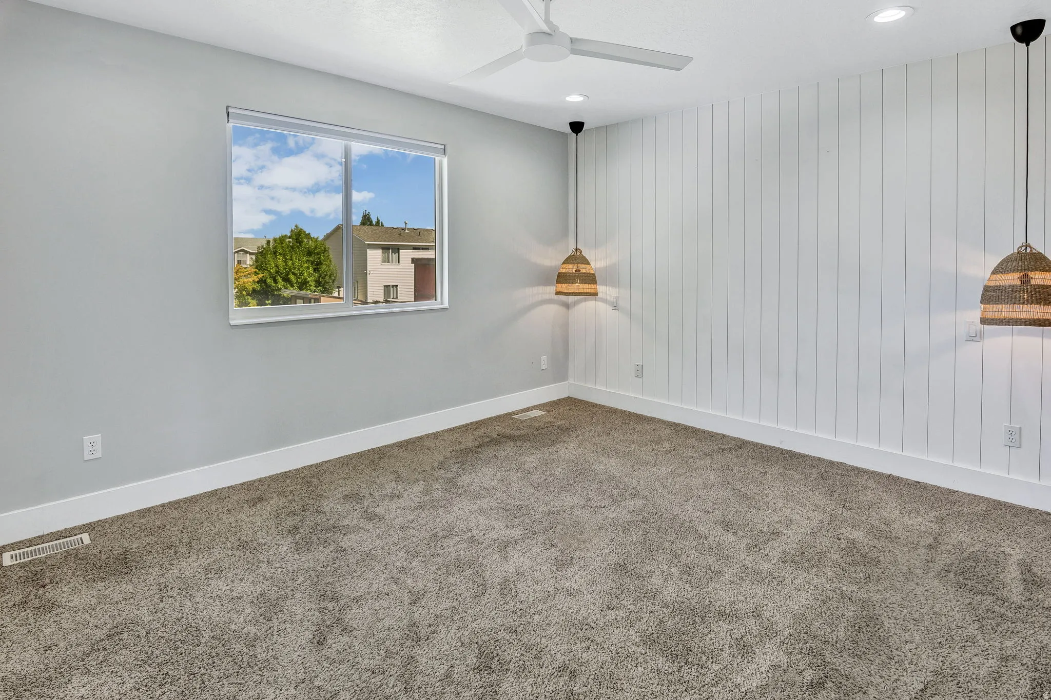 Interior room featuring plush gray carpeting, a window with white trim, and a white shiplap accent wall