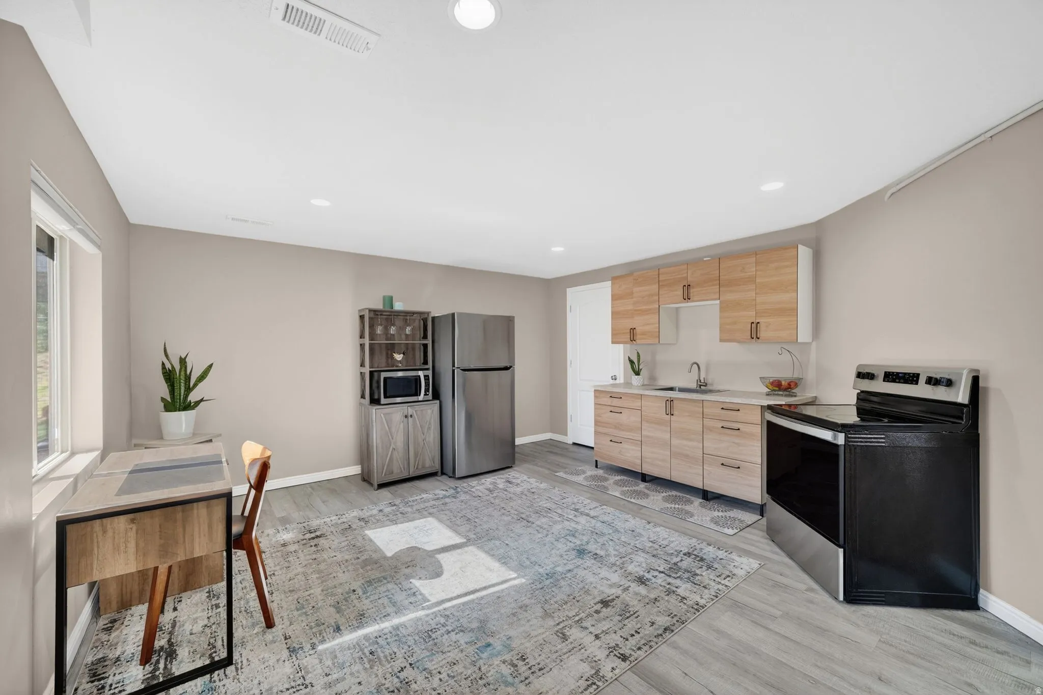 Kitchenette area featuring wood-finish cabinetry, stainless steel appliances, and wood-finish flooring