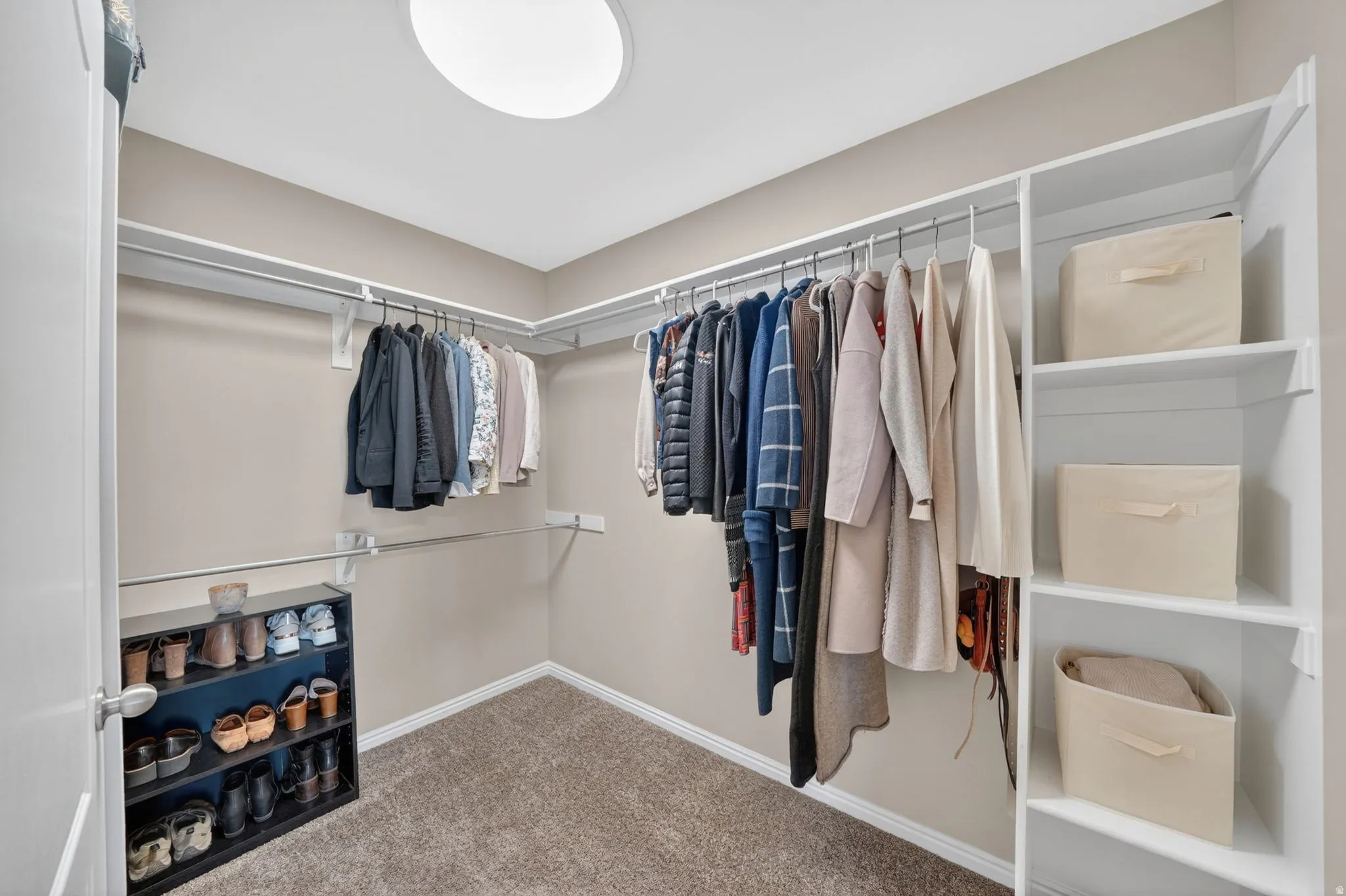 Expansive walk-in closet featuring white built-in shelving, chrome hanging rods, recessed ceiling lighting, and neutral-toned carpeting