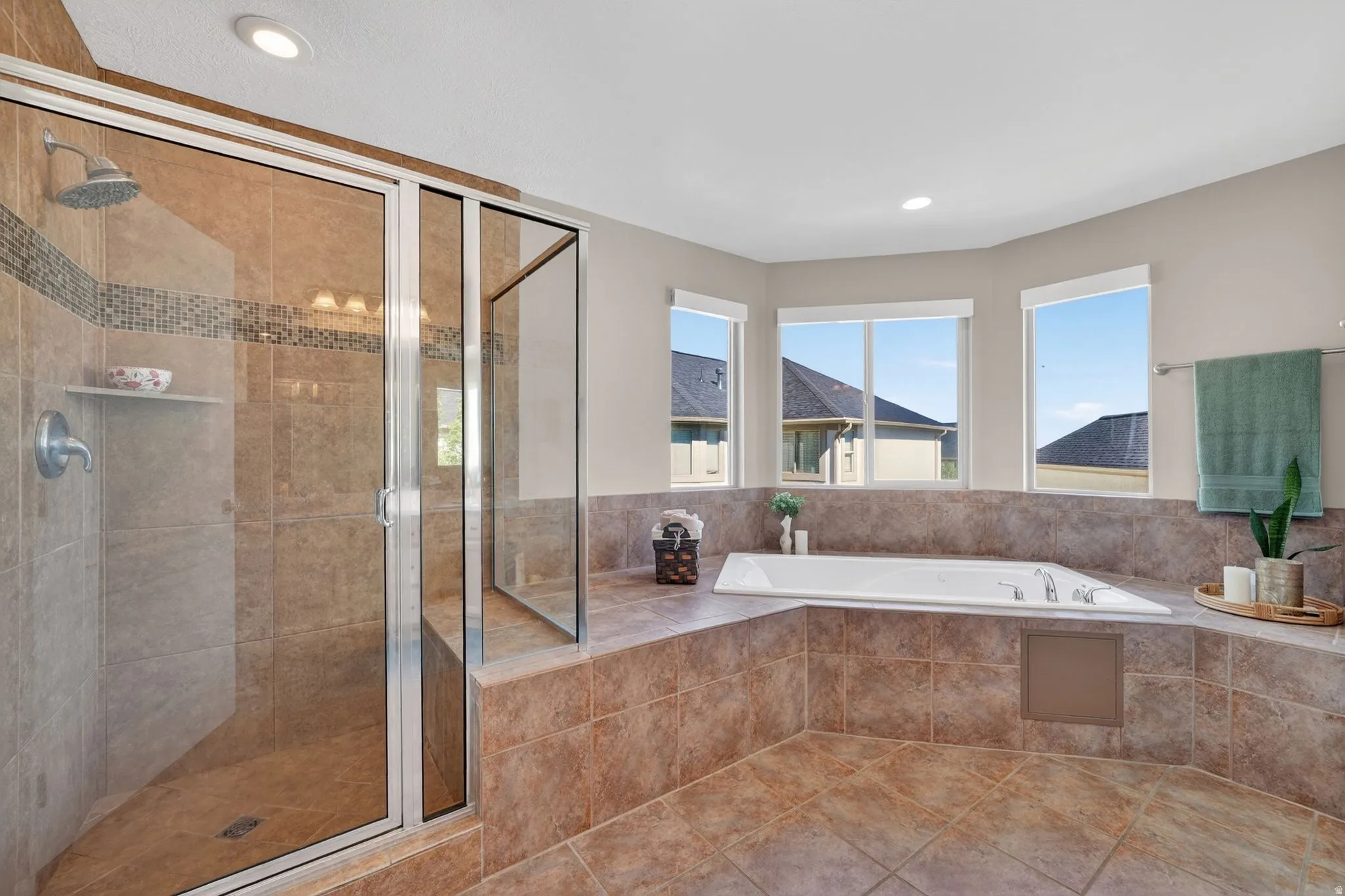 Tiled bathroom featuring a glass-enclosed shower with a built-in shelf and a mosaic accent band