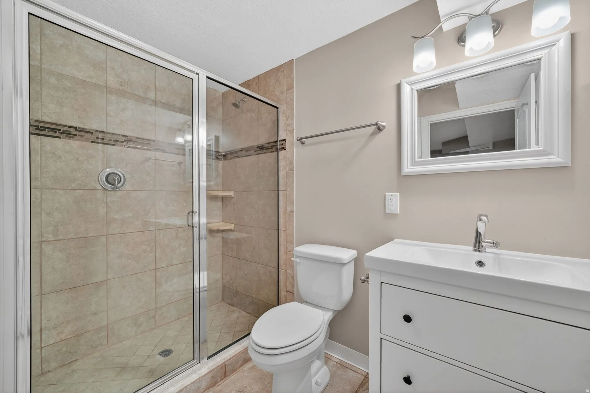 Contemporary bathroom featuring a glass-enclosed shower with full-height tile surround and decorative accent banding
