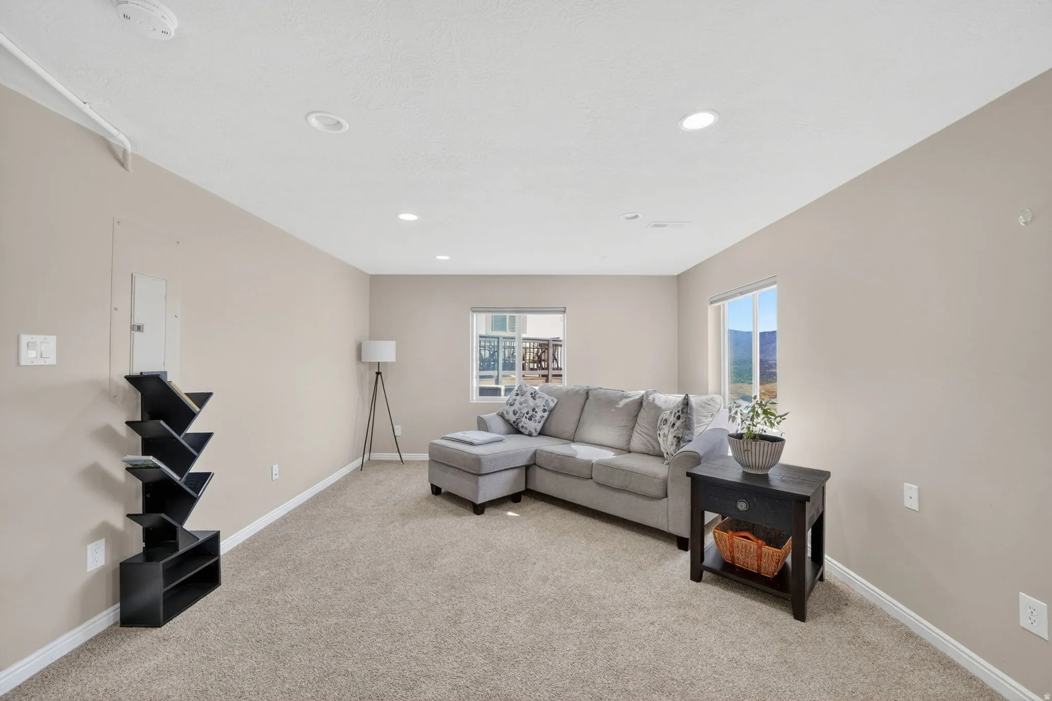 Recessed lighting illuminates the carpeted living space with neutral wall tones