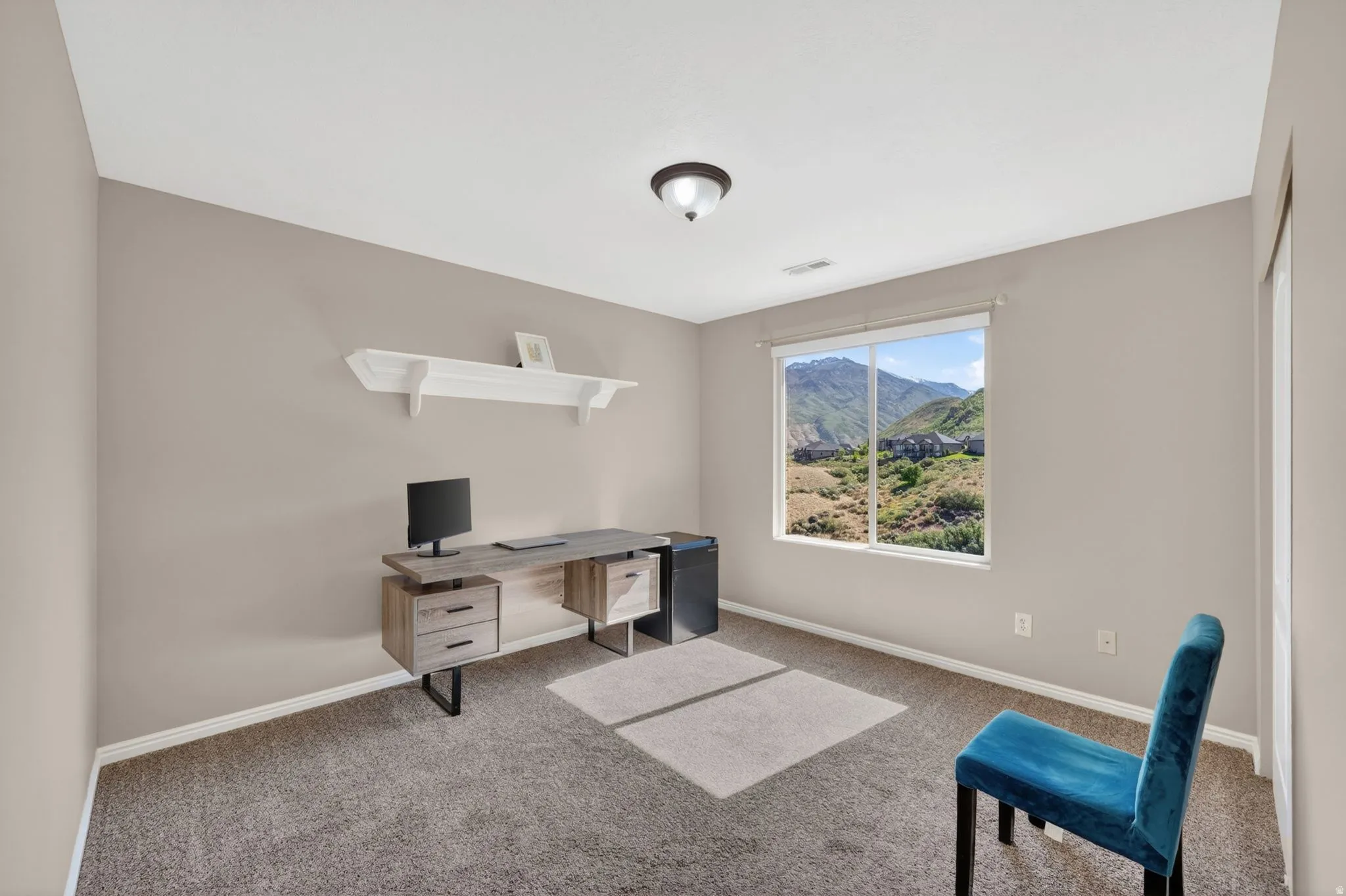 Room featuring a large window with mountain scenery, neutral-toned walls, and carpet flooring