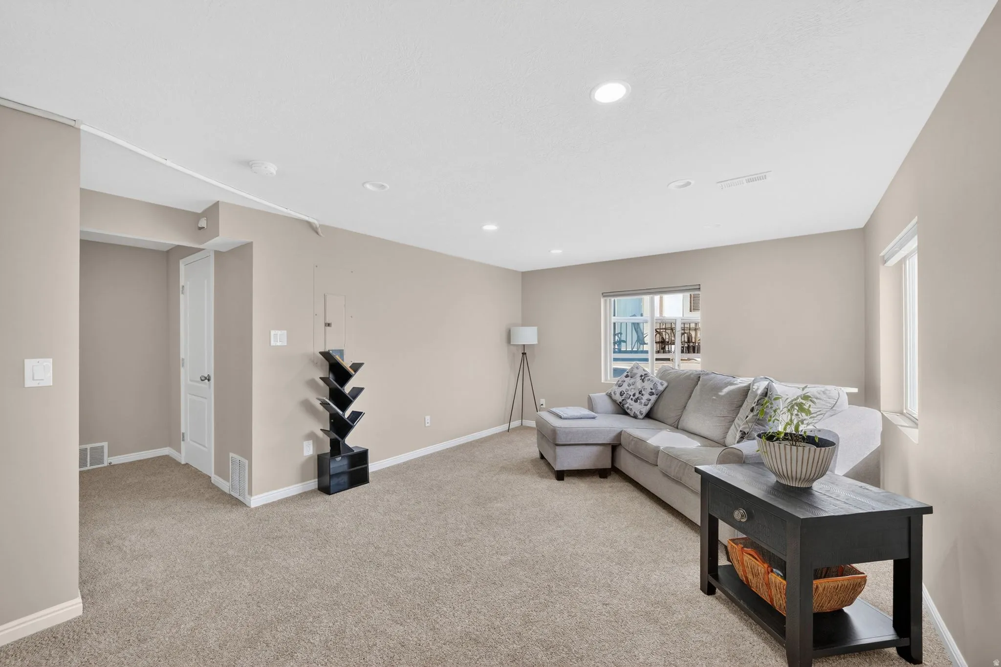 Carpeted recreation room featuring light tan walls, recessed ceiling lighting, and multiple windows