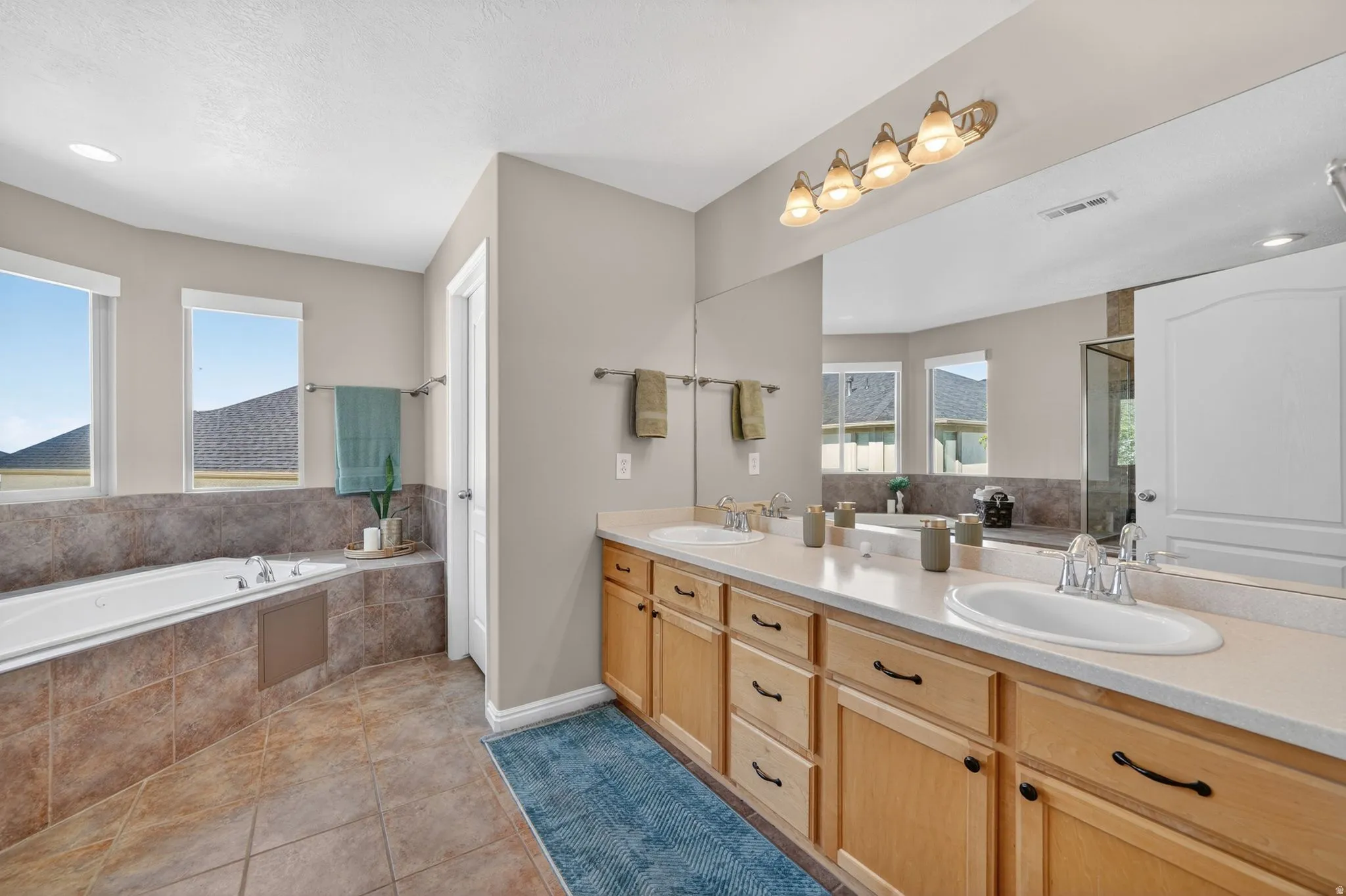 Dual vanity with light wood cabinetry, white countertops, and undermount sinks