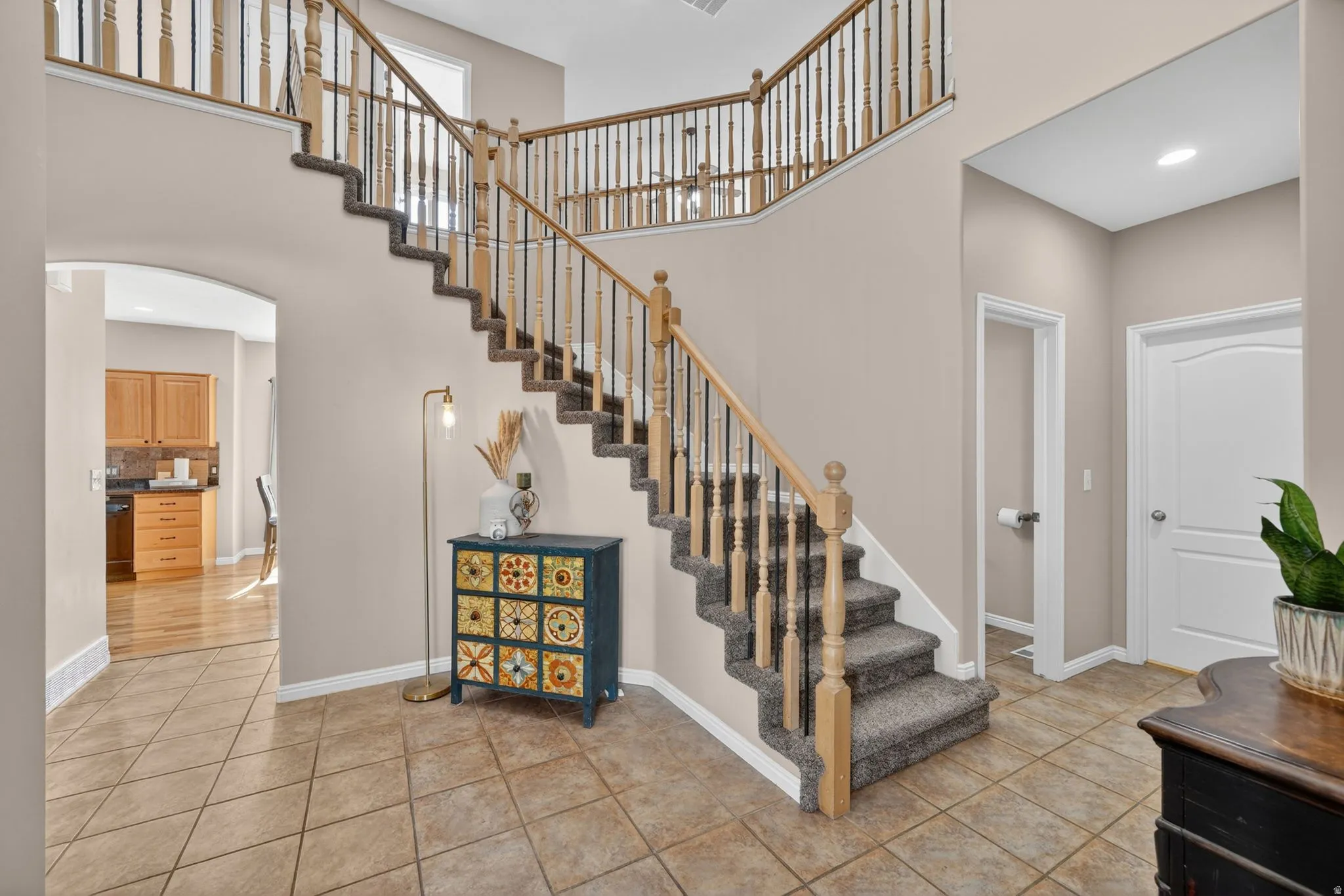 Grand entryway featuring a split staircase with wood balusters and carpeted treads