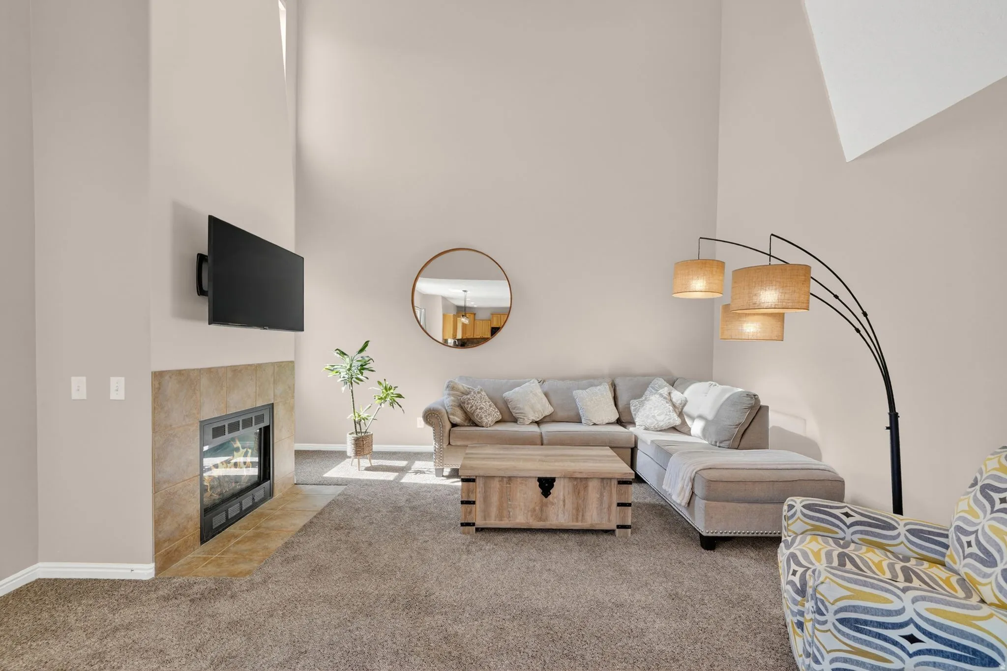 Living area featuring vaulted ceilings, a built-in fireplace with tile surround, and neutral carpet flooring