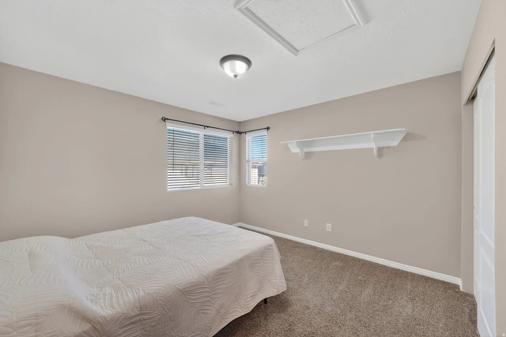 Bedroom featuring neutral-toned walls, carpeted flooring, and a flush-mount ceiling light
