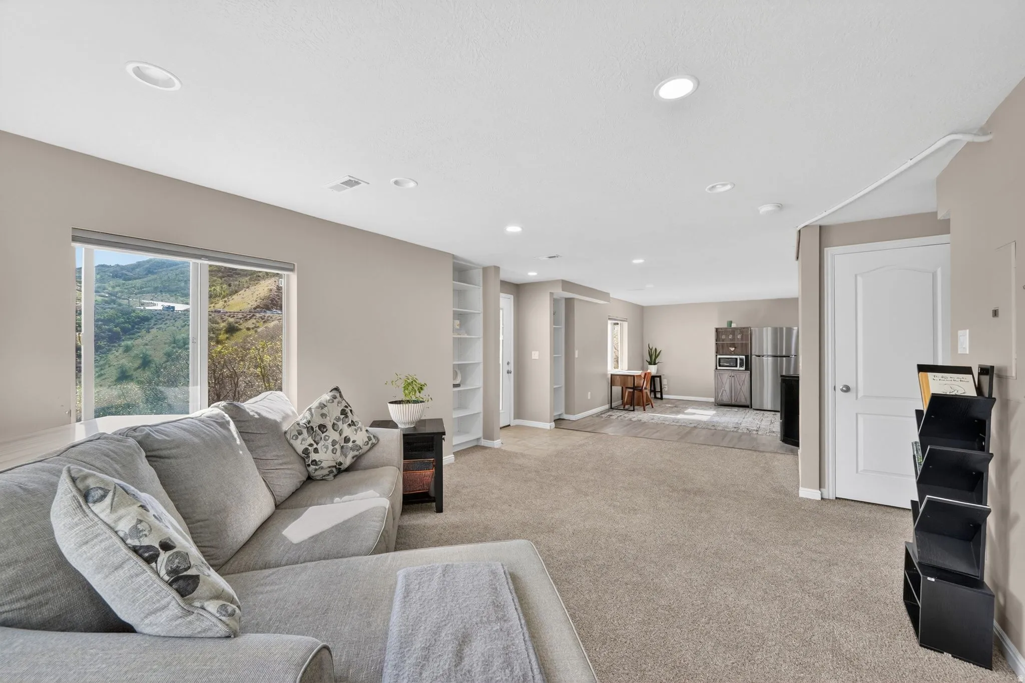 Spacious living area featuring a large window, recessed lighting, neutral paint, and built-in shelving