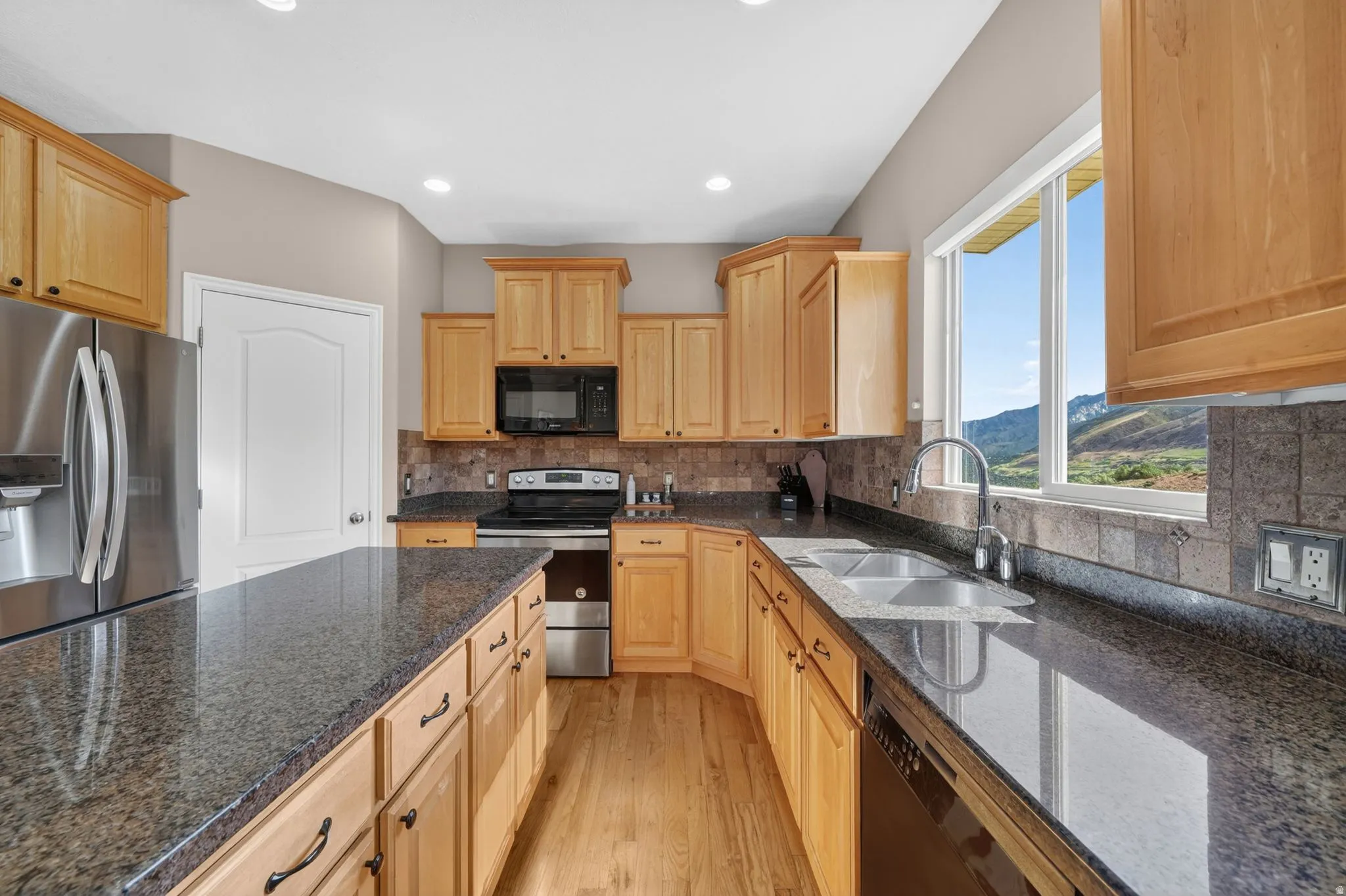 Kitchen featuring wood-finish cabinetry, dark speckled countertops, and a full tile backsplash