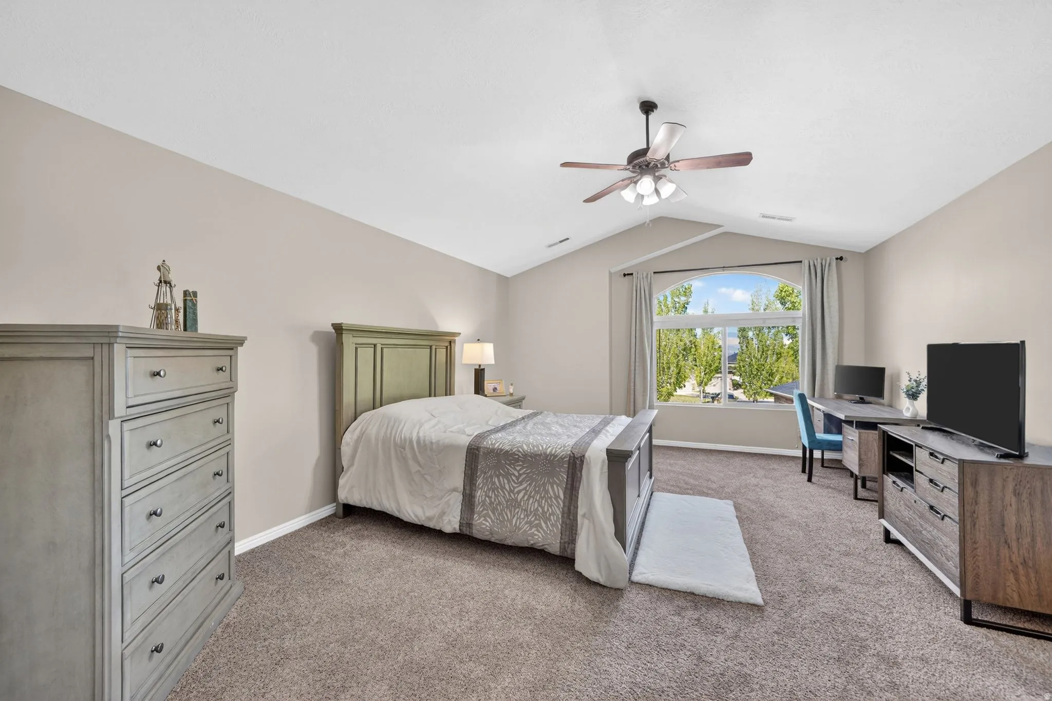 Carpeted room featuring a vaulted ceiling and an arched window