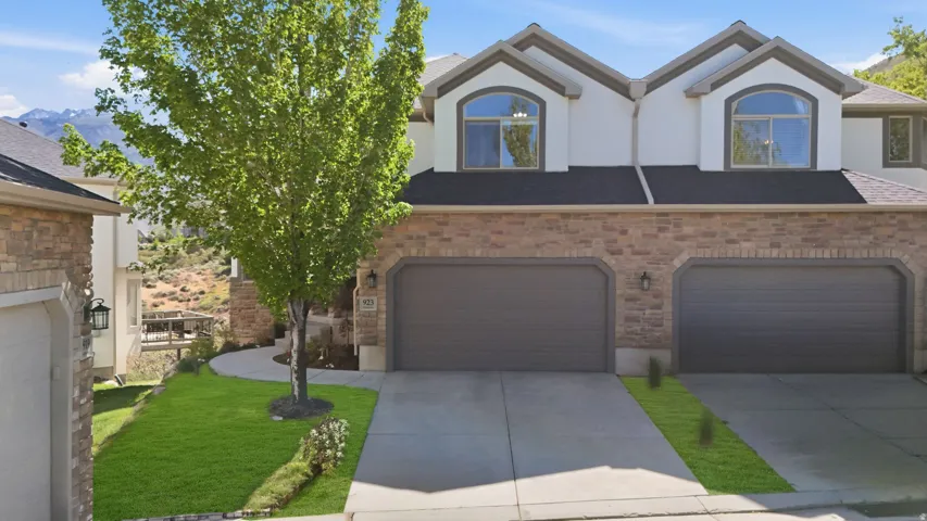 Façade with brick and stucco finishes, featuring two arched dormer windows and a multi-car garage