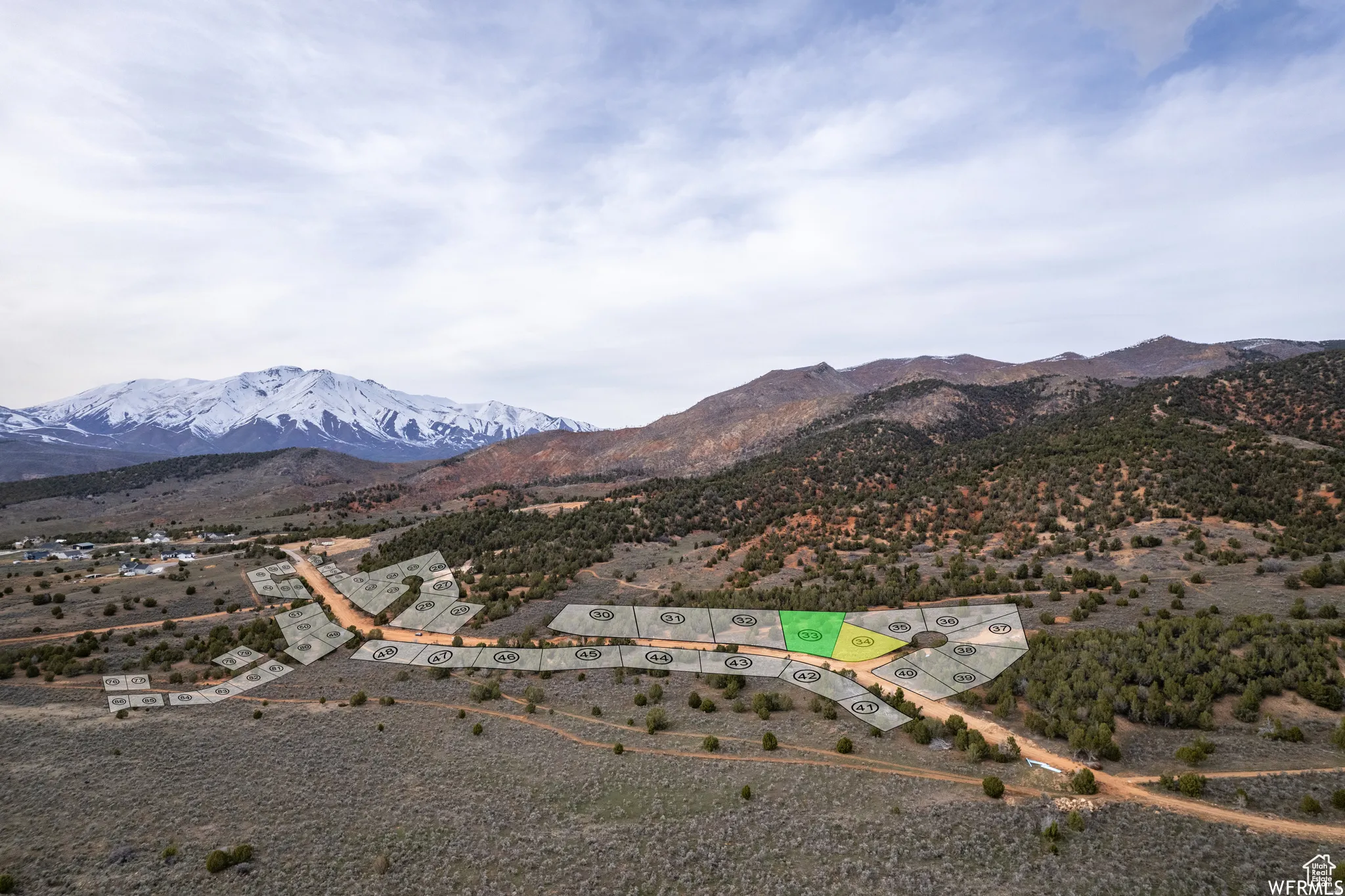 Aerial perspective of a developing residential area with marked lots, surrounded by natural mountainous terrain