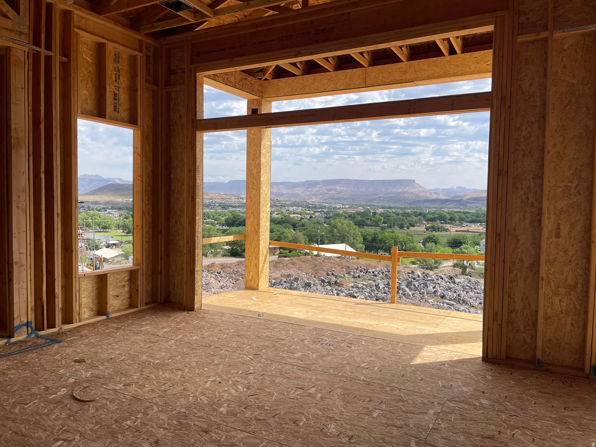 Expansive outdoor living area, showcasing a panoramic mountain and valley backdrop, with a generous window opening and natural wood framing